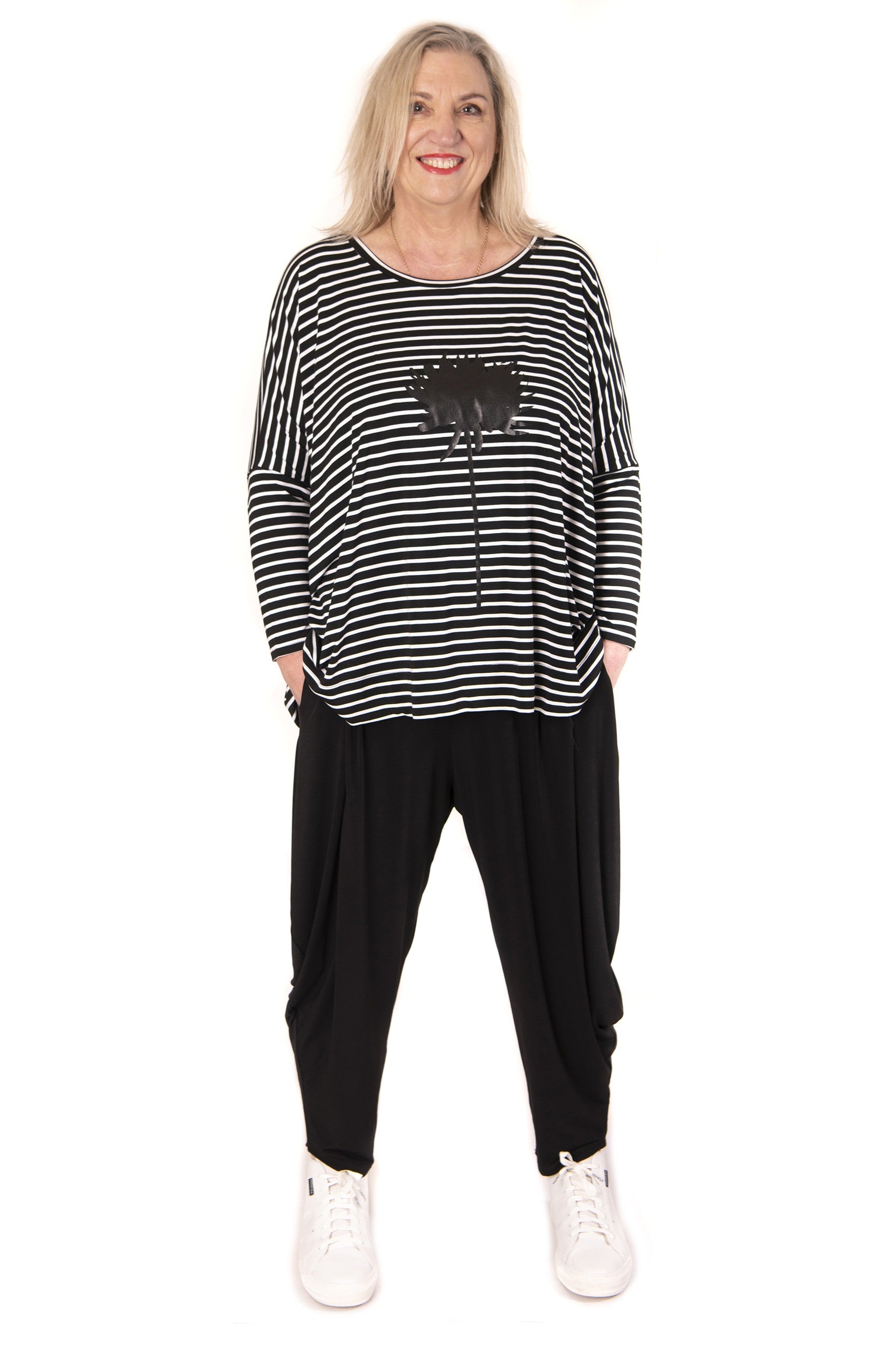 Woman wearing a black and white striped top with screenprint and black pants on a white background