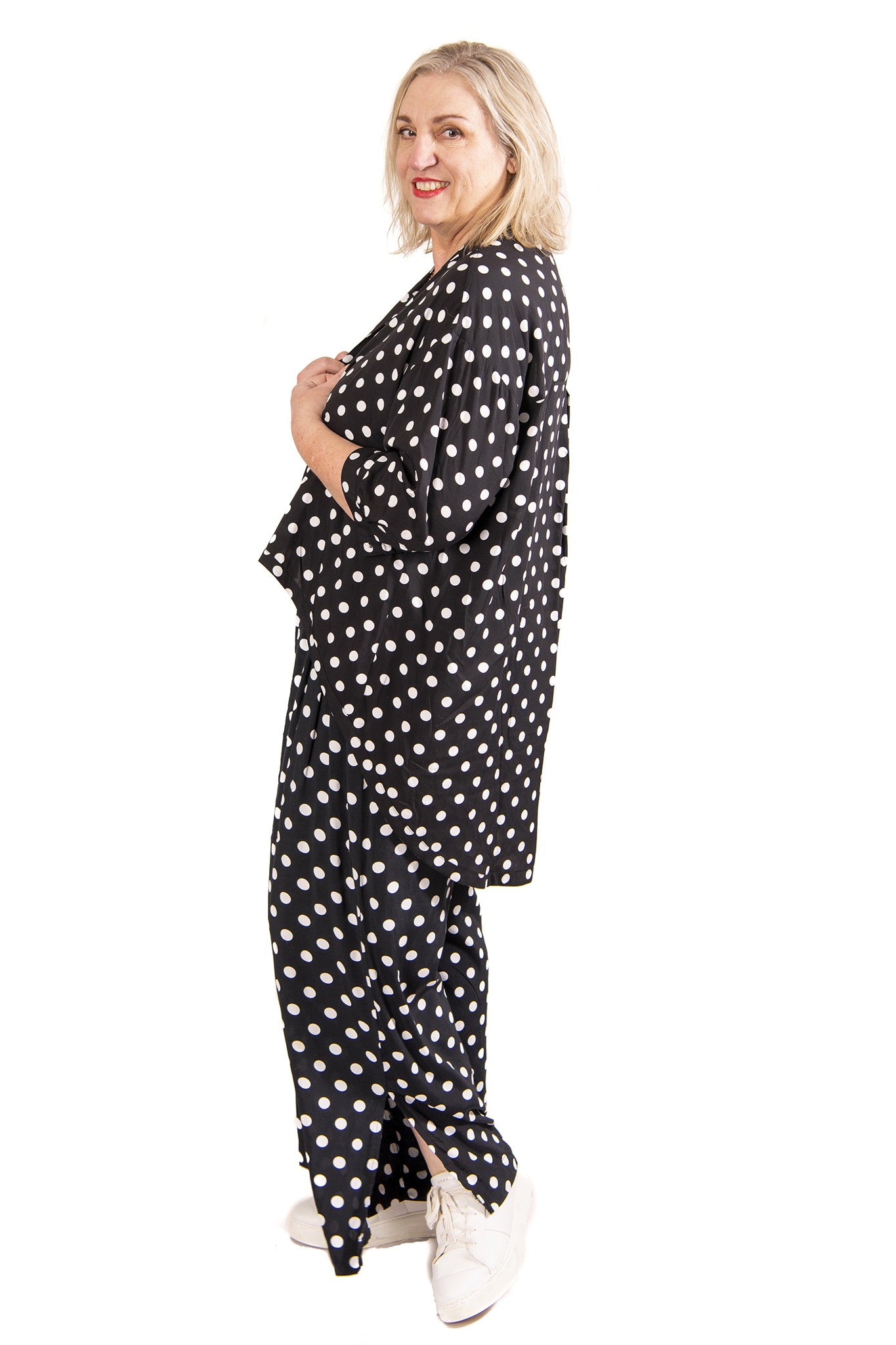 Woman wearing a black polka dot top and pants on a white background