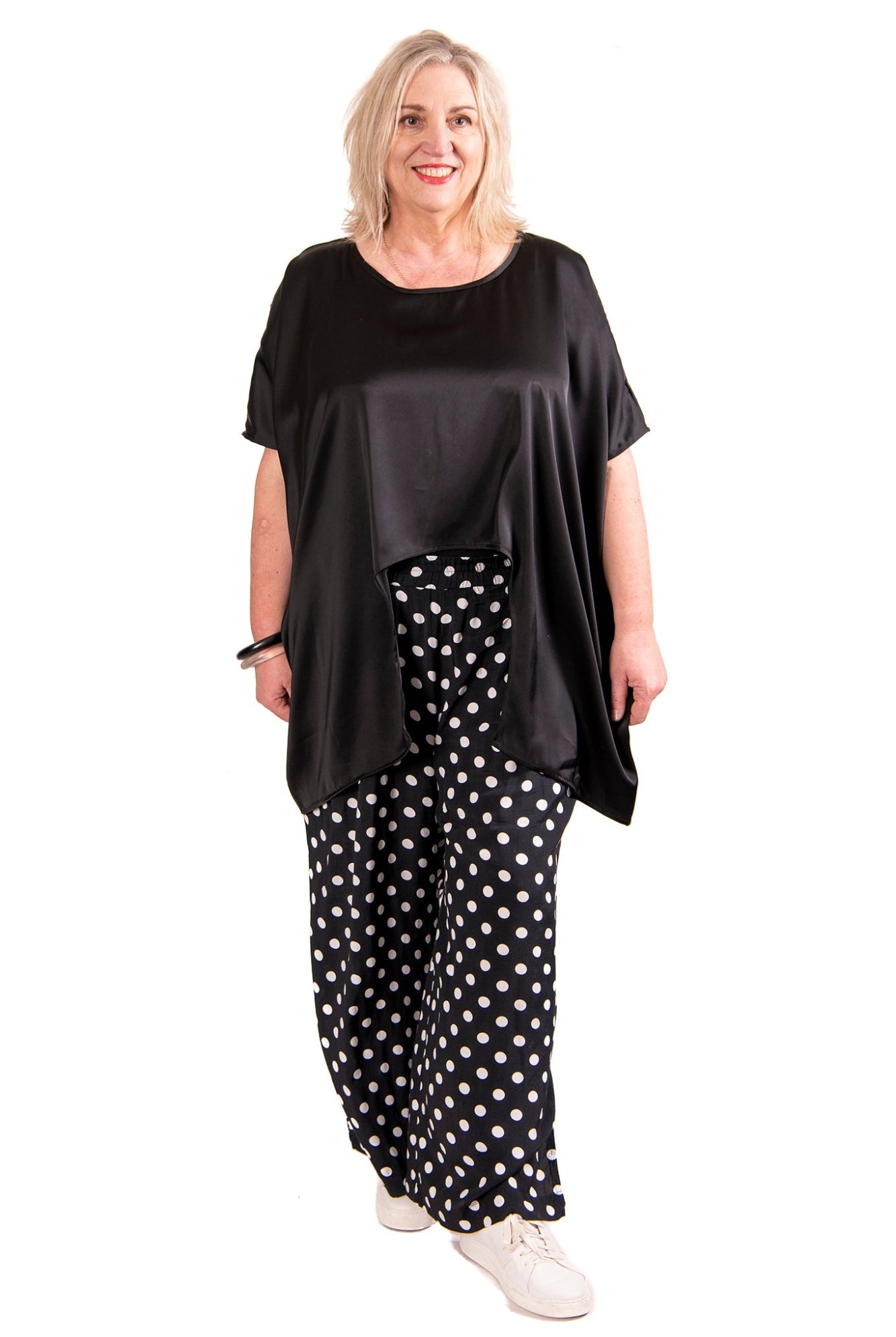 black satin curve hem top and spot pants worn by model against white background