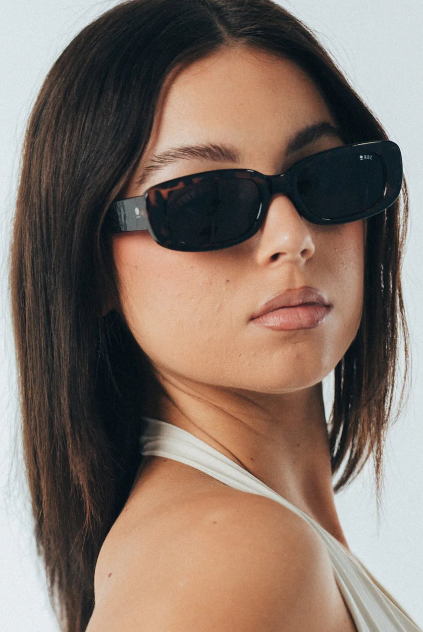 Woman wearing dark sunglasses against a light background