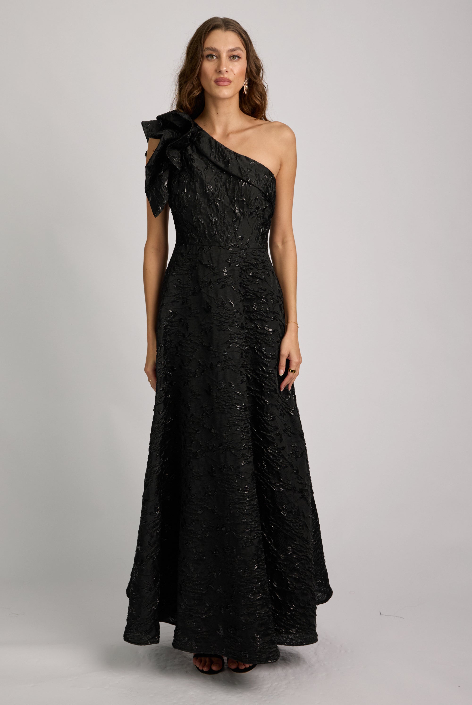 Woman wearing a black one-shoulder dress against a gray background