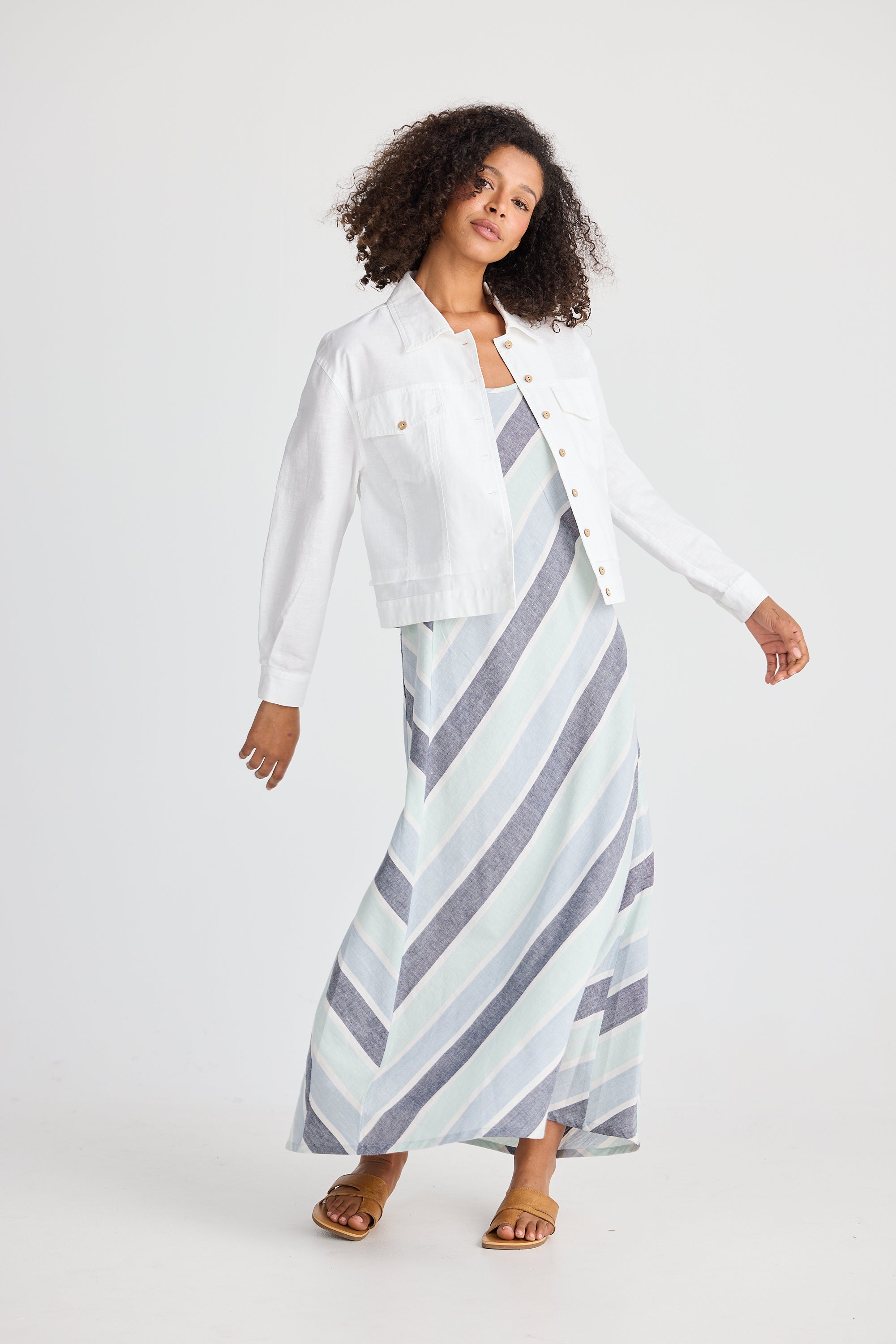 Woman wearing a white jacket and a long, patterned skirt on a plain background