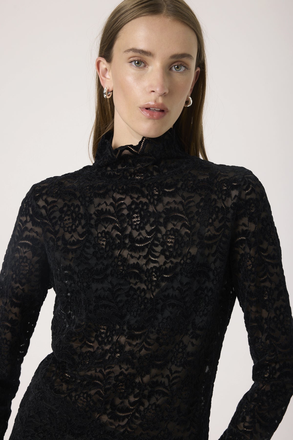 Woman wearing a black lace top against a white background