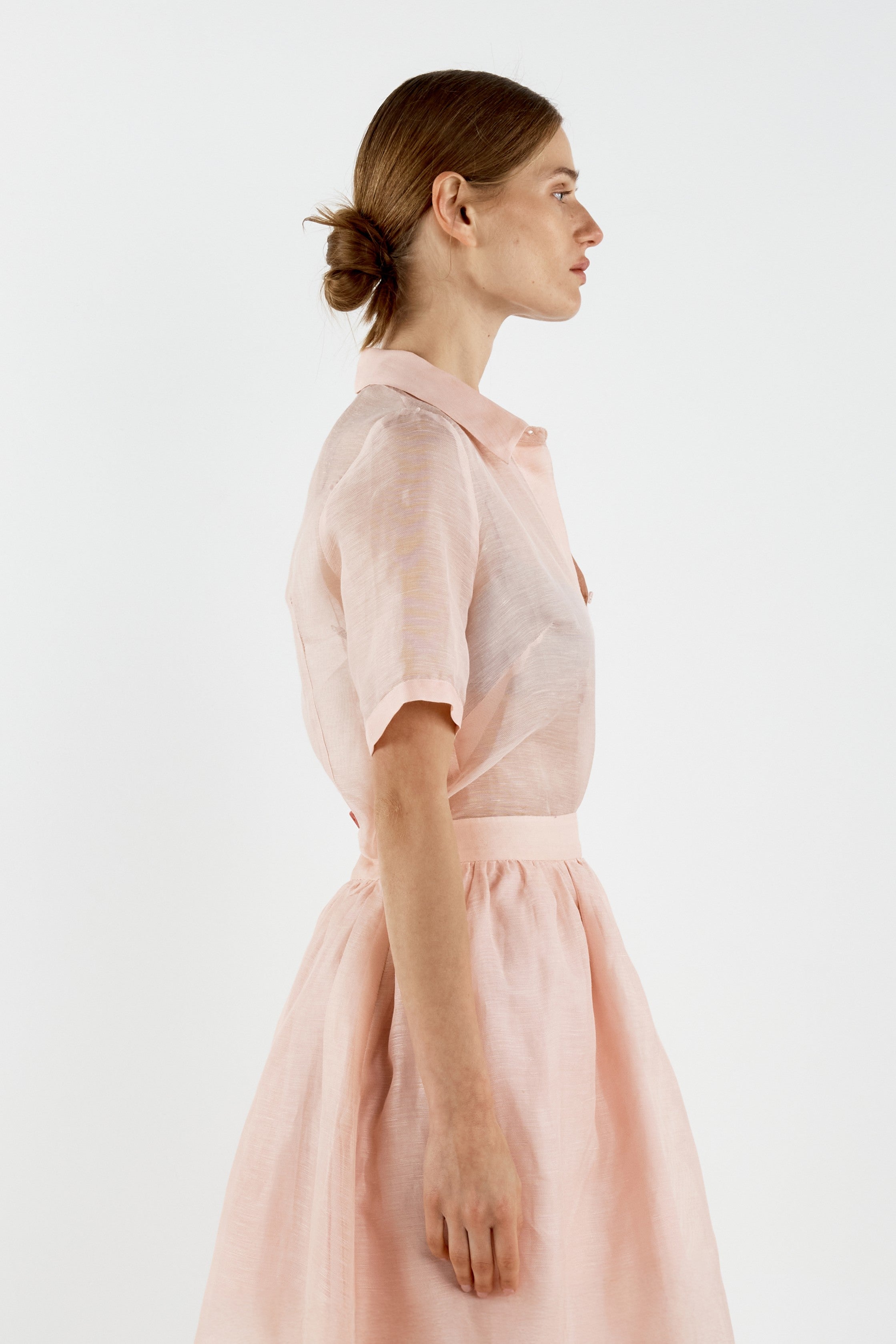 Woman wearing a light pink shirt against a white background