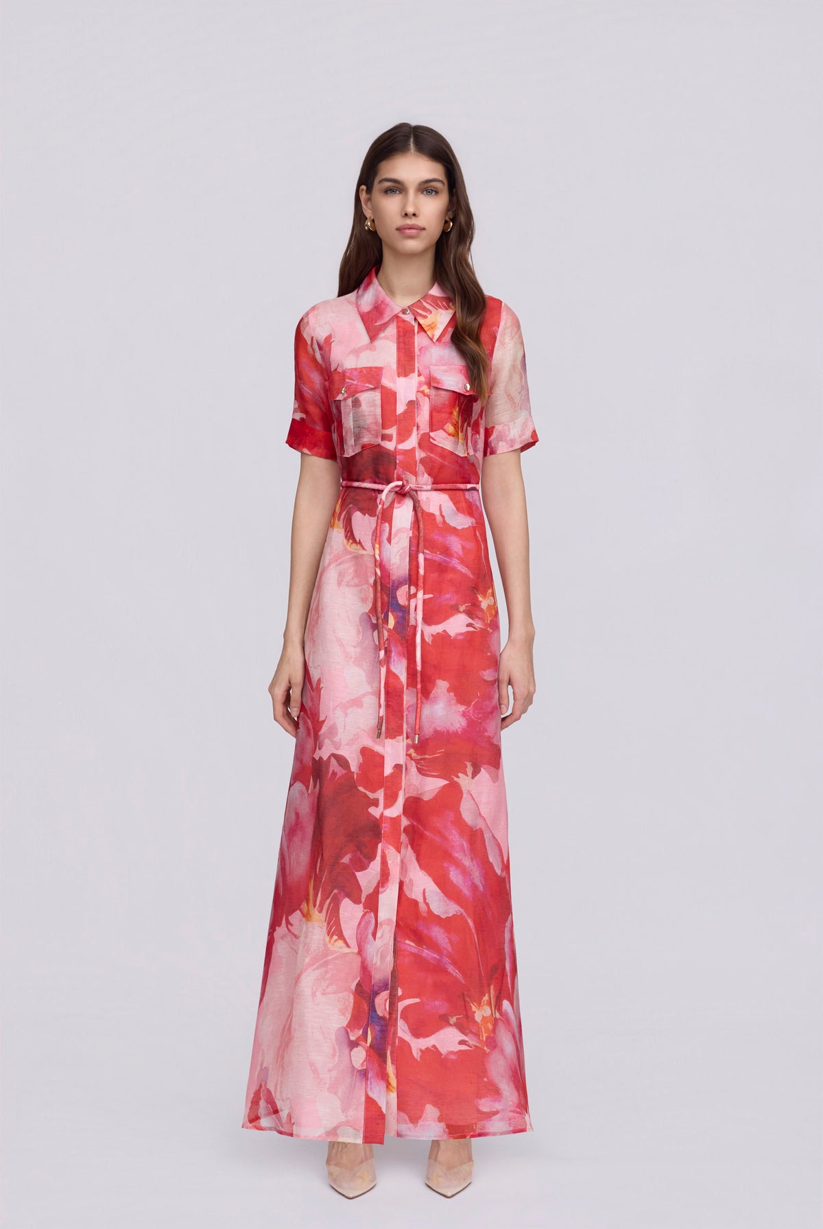 women wearing a pink and red floral maxi dress with a removable waist tie on a plain background
