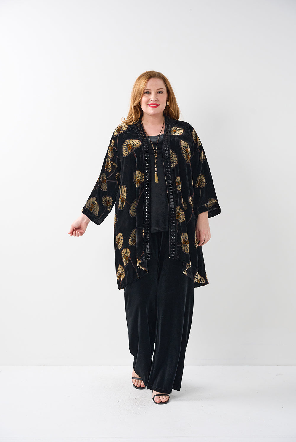 Woman wearing a black outfit with gold patterns on a white background