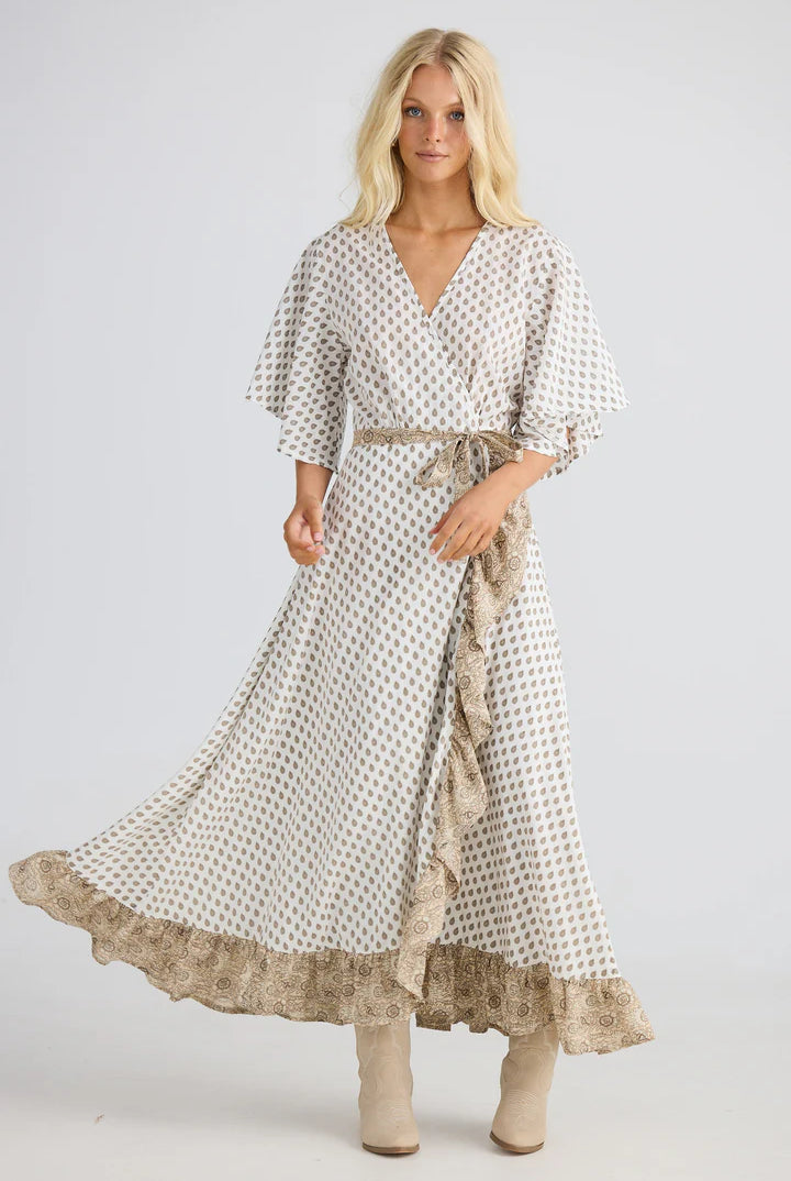 Woman wearing a long, patterned dress with a belt on a white background