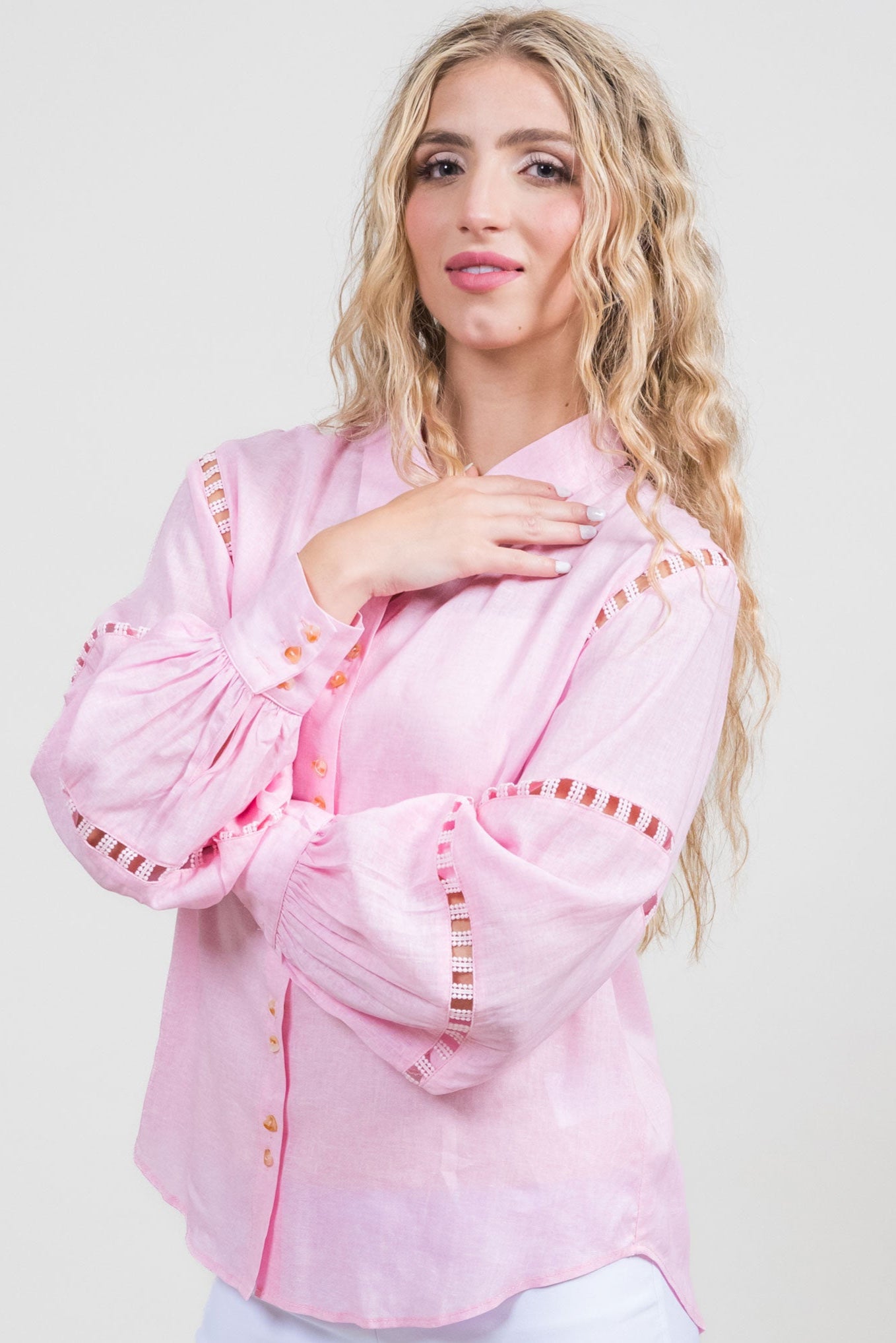 Woman wearing a pink blouse with decorative sleeves on a white background