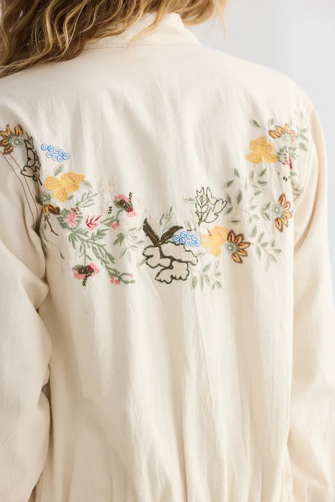 Beige shirt with floral embroidery on a plain background