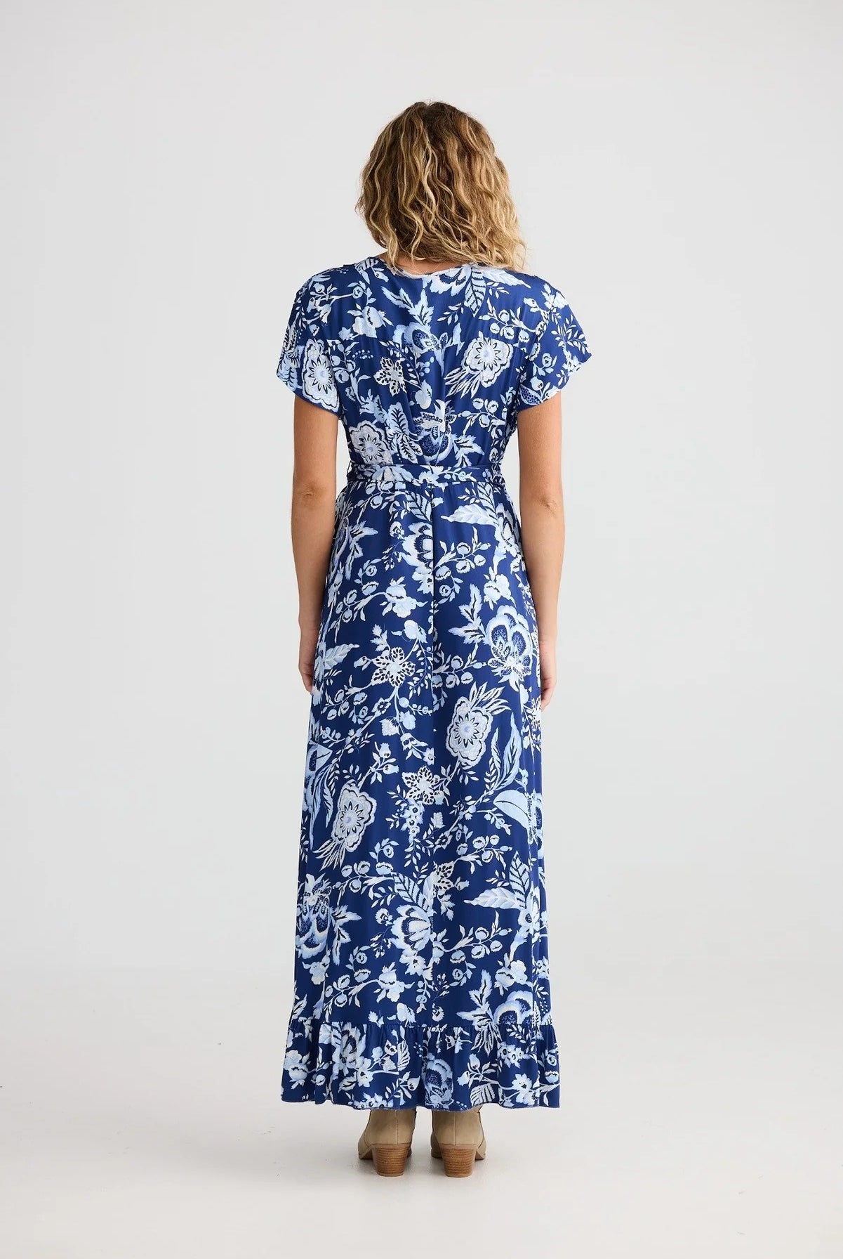 Woman wearing a blue floral dress on a white background back