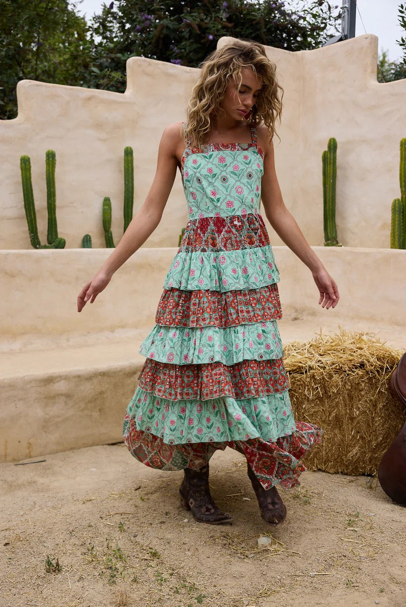 Woman wearing a floral tiered dress standing in front of a desert-like setting with cacti.