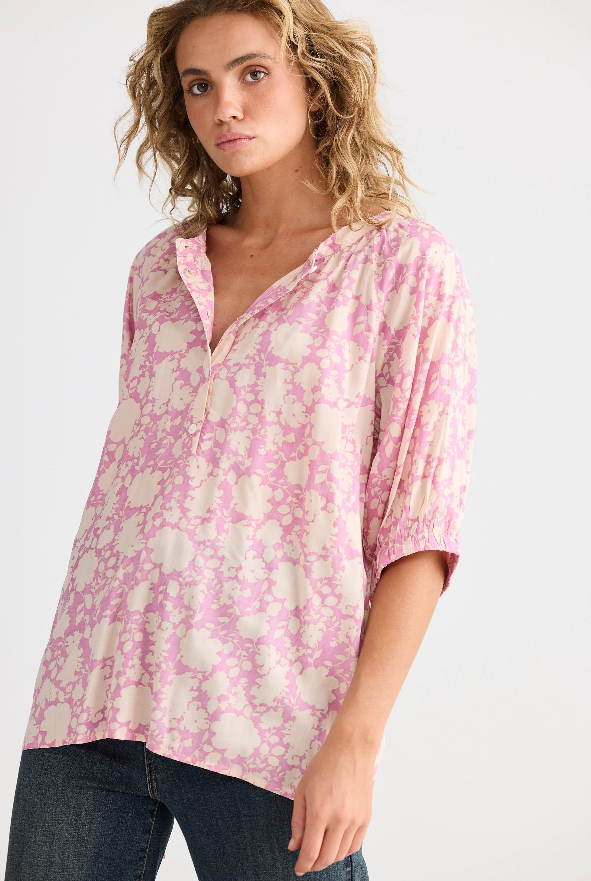 Woman wearing a pink floral blouse on a white background