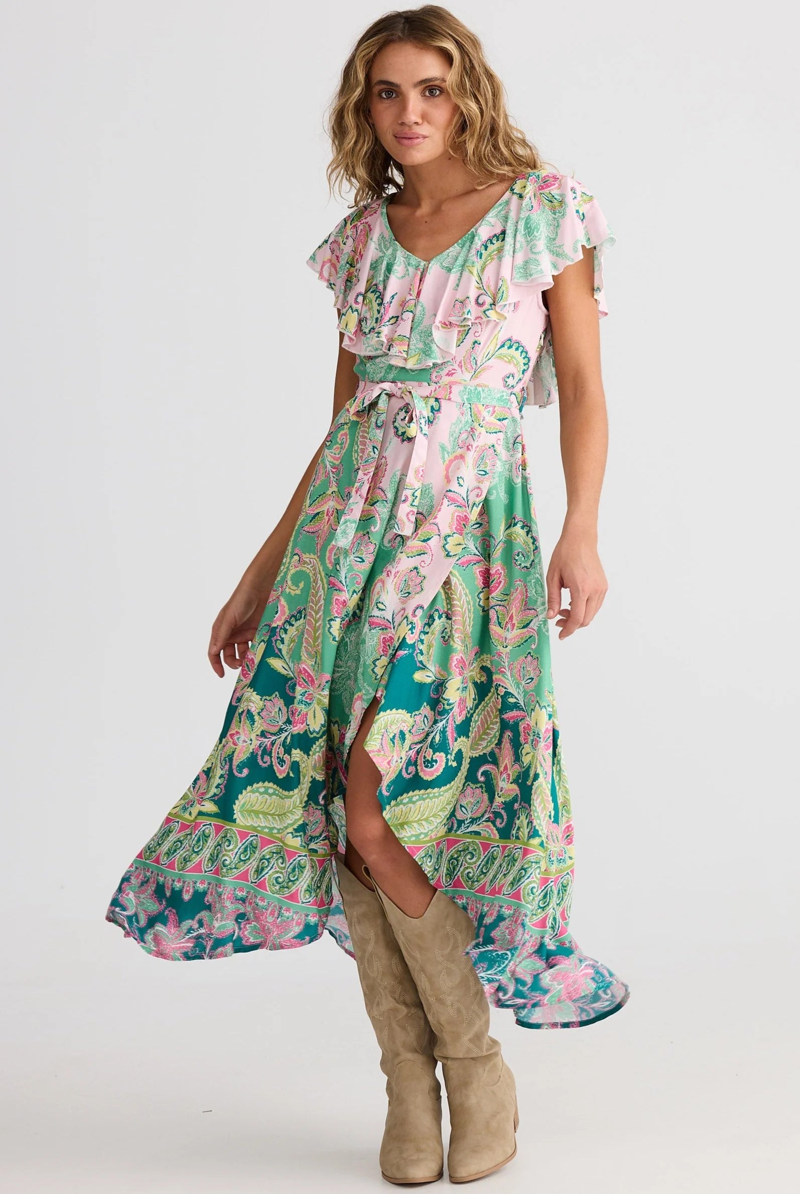 Woman wearing a colorful patterned dress with beige boots on a white background