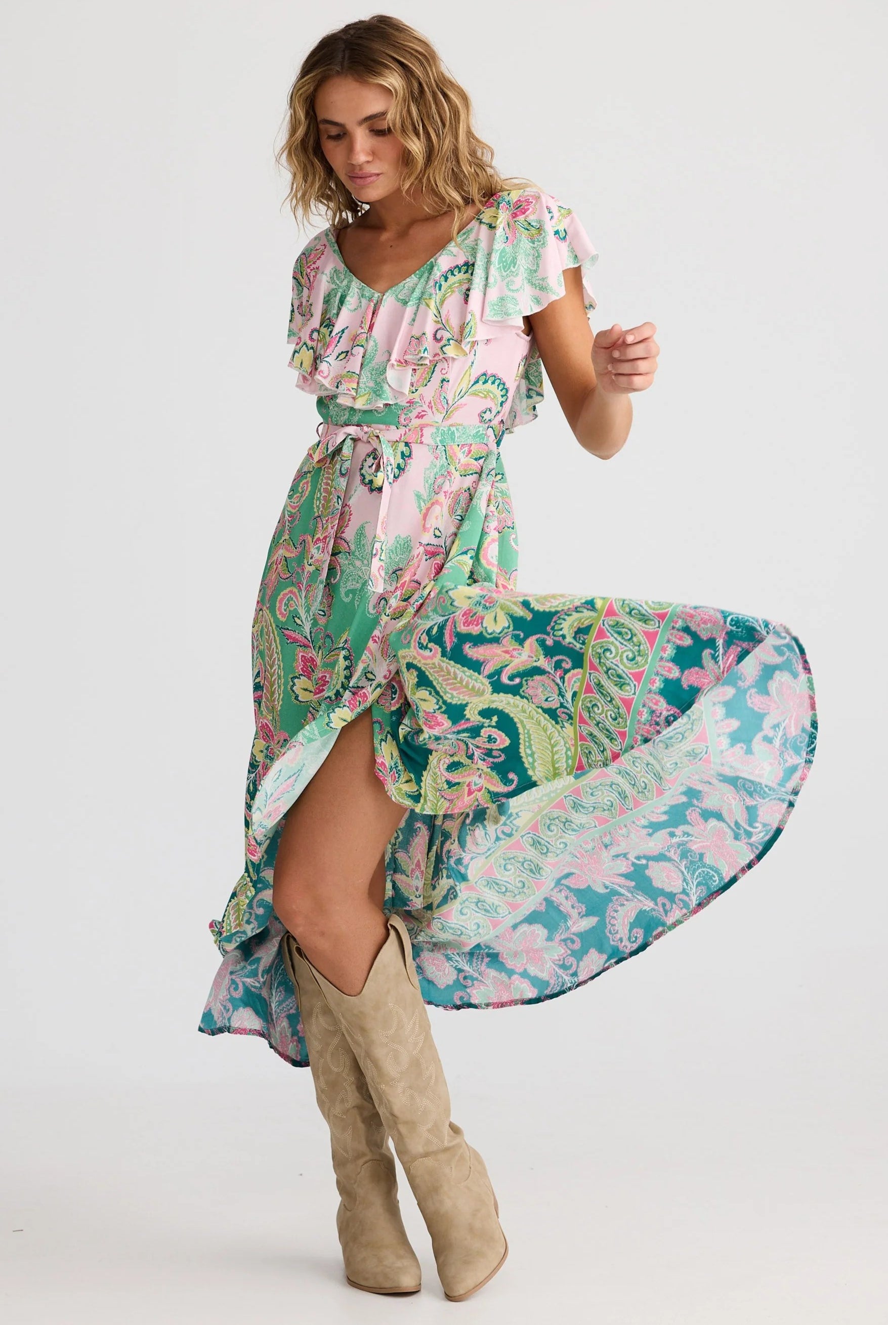 Woman wearing a colorful floral dress with beige knee-high boots on a white background