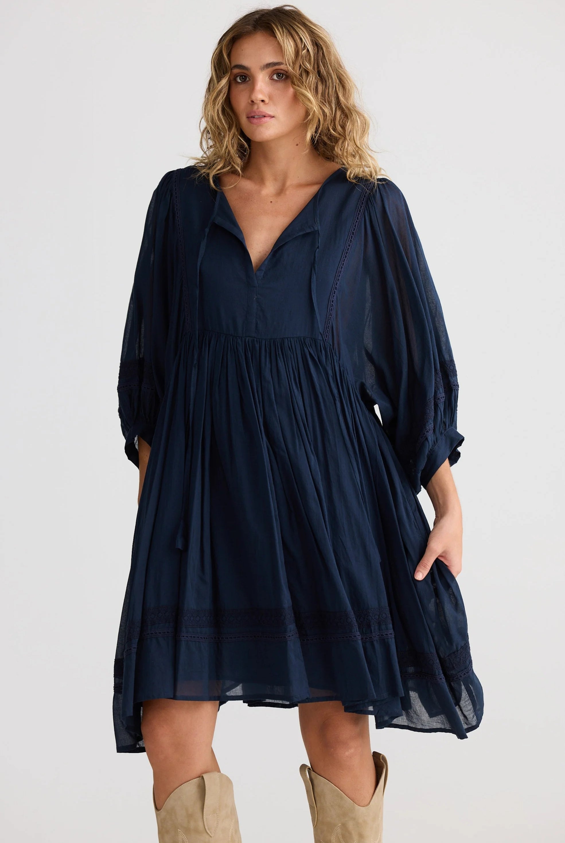 Woman wearing a navy blue dress with long sleeves on a white background