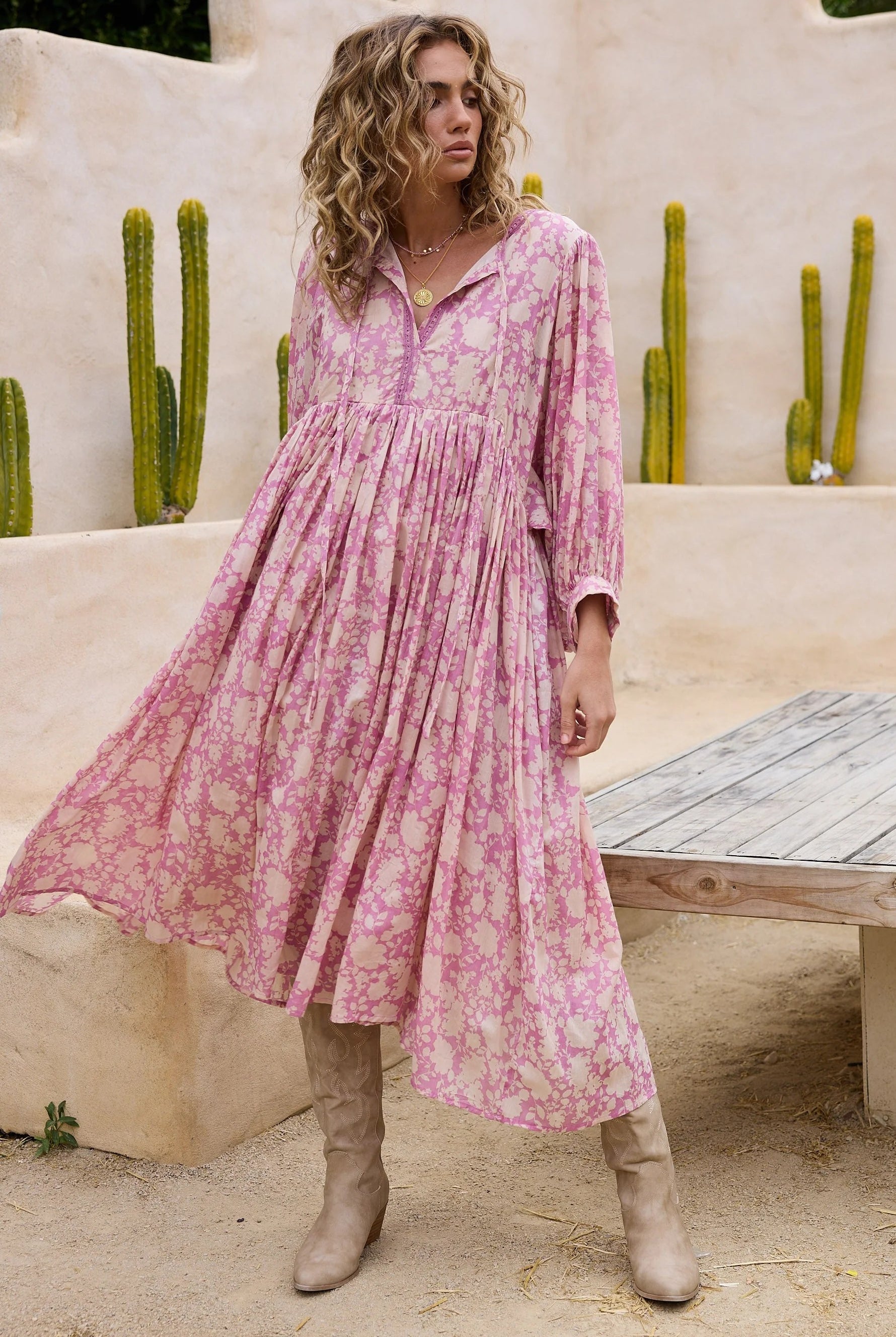 Woman in a pink floral dress standing in front of cacti