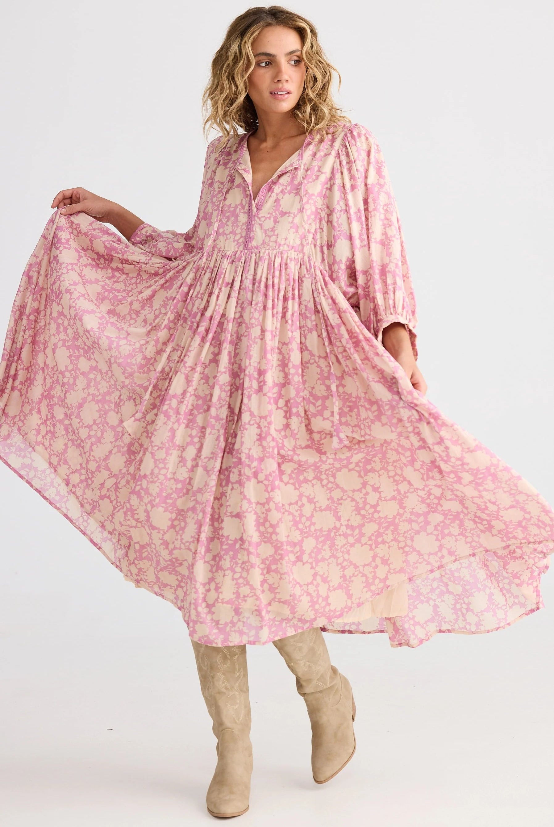 Woman wearing a pink floral dress with long sleeves on a white background