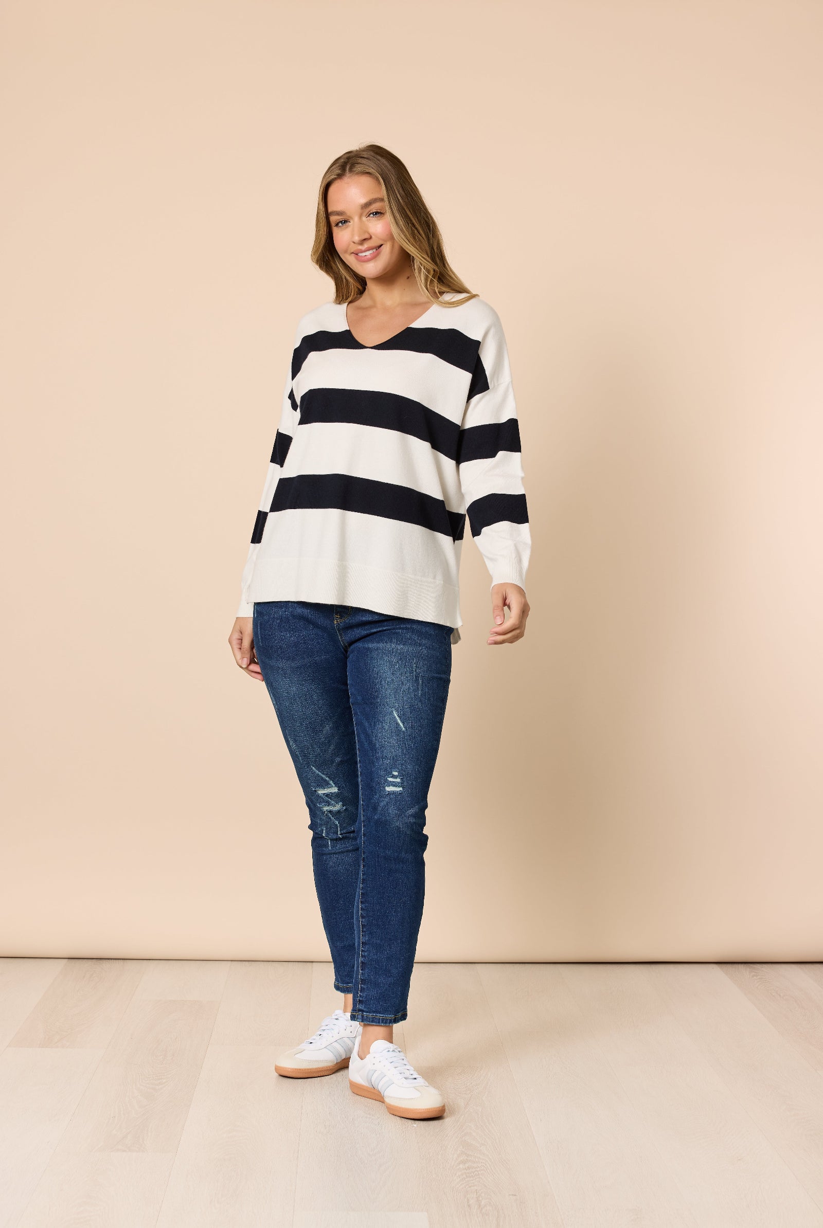 Woman wearing a striped sweater and jeans against a beige background