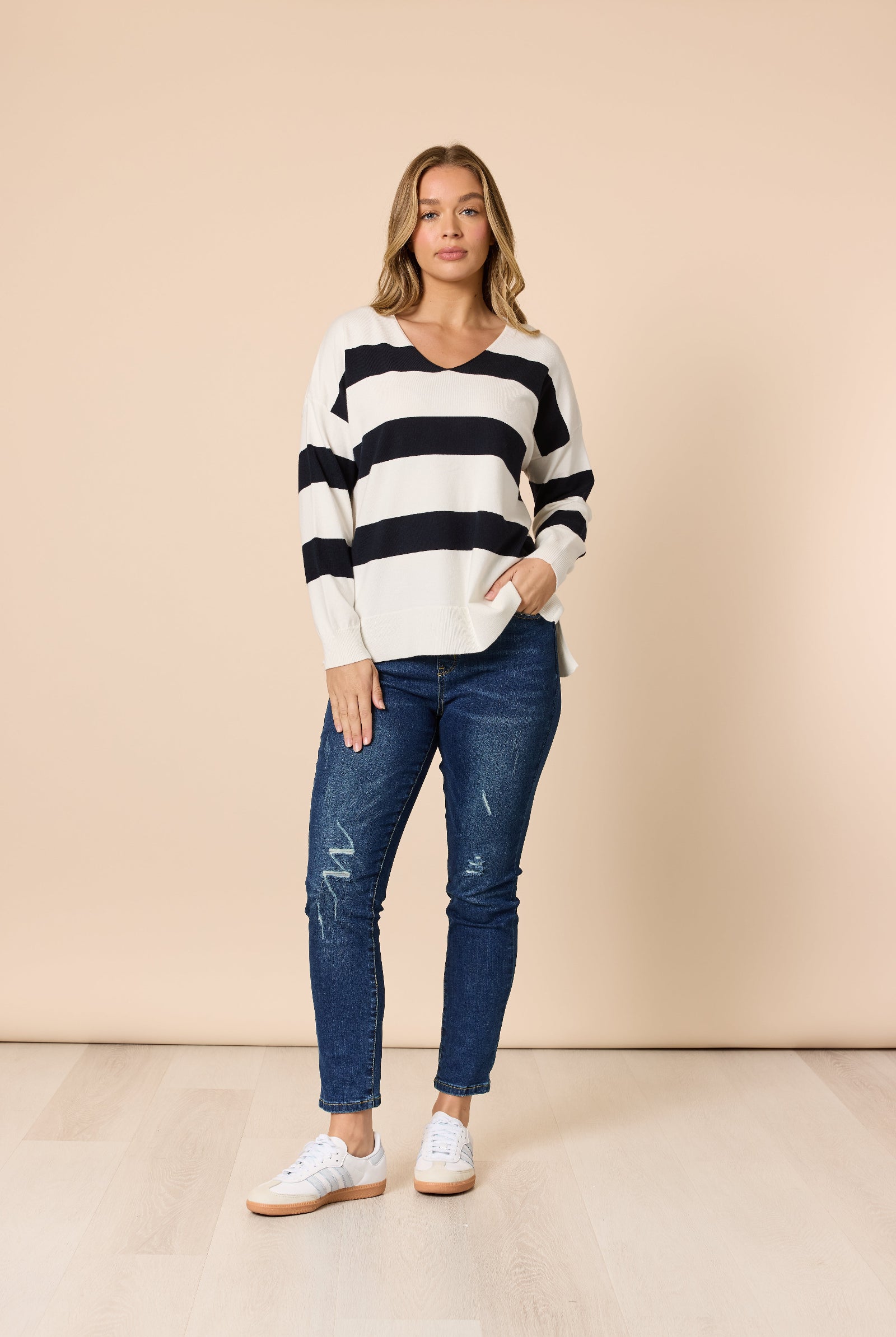 Woman wearing a striped sweater and jeans against a beige background