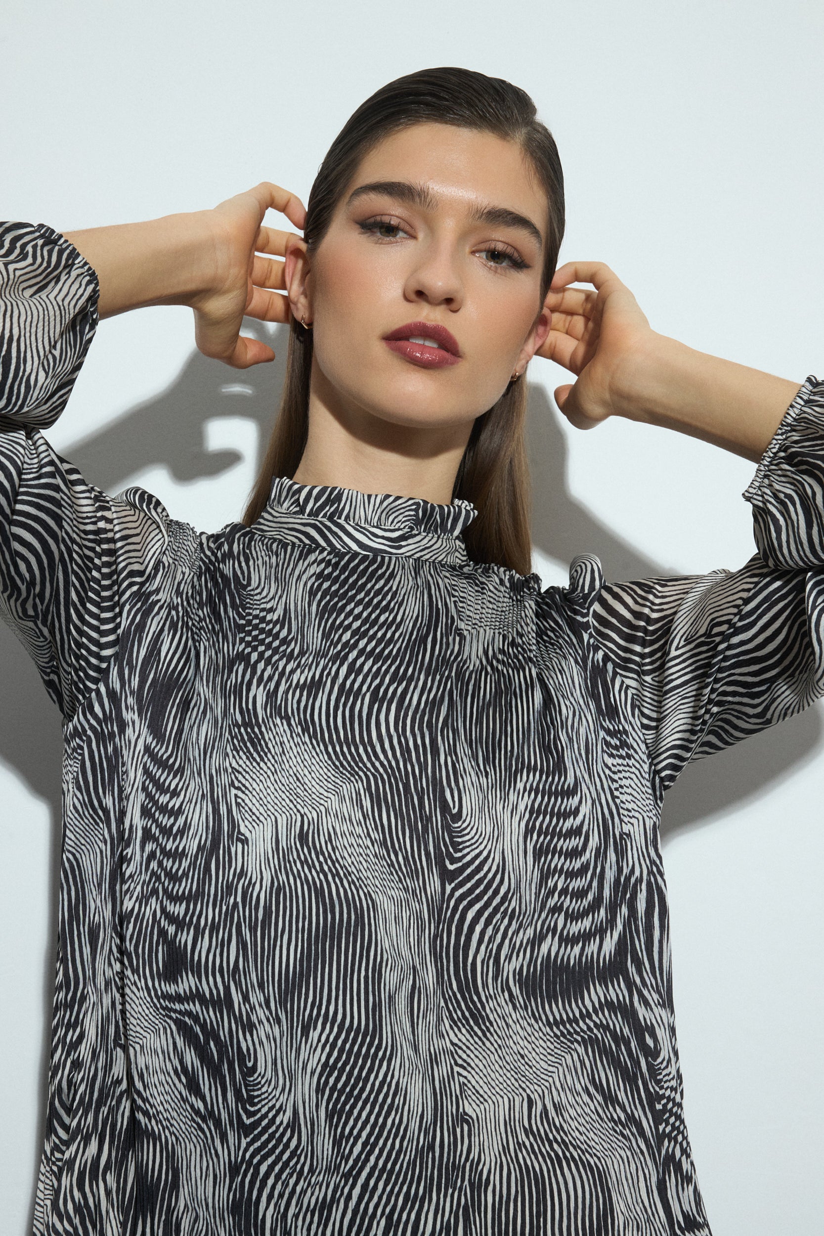 Woman wearing a black and white patterned dress and black boots on a white background close up