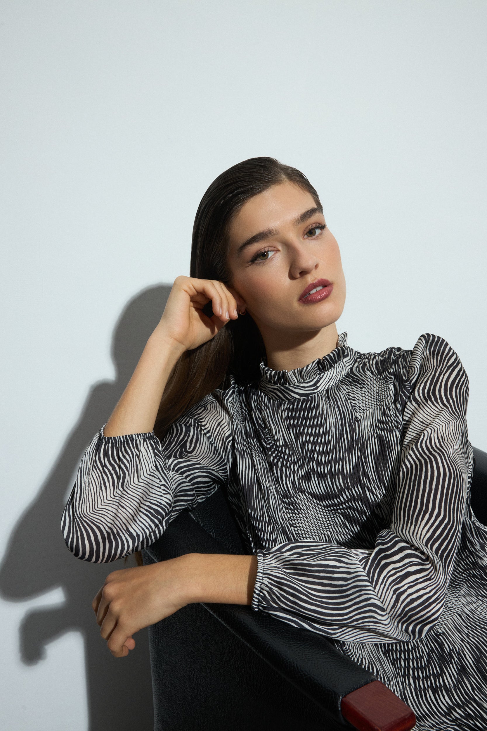 Woman wearing a black and white patterned dress and black boots on a white background