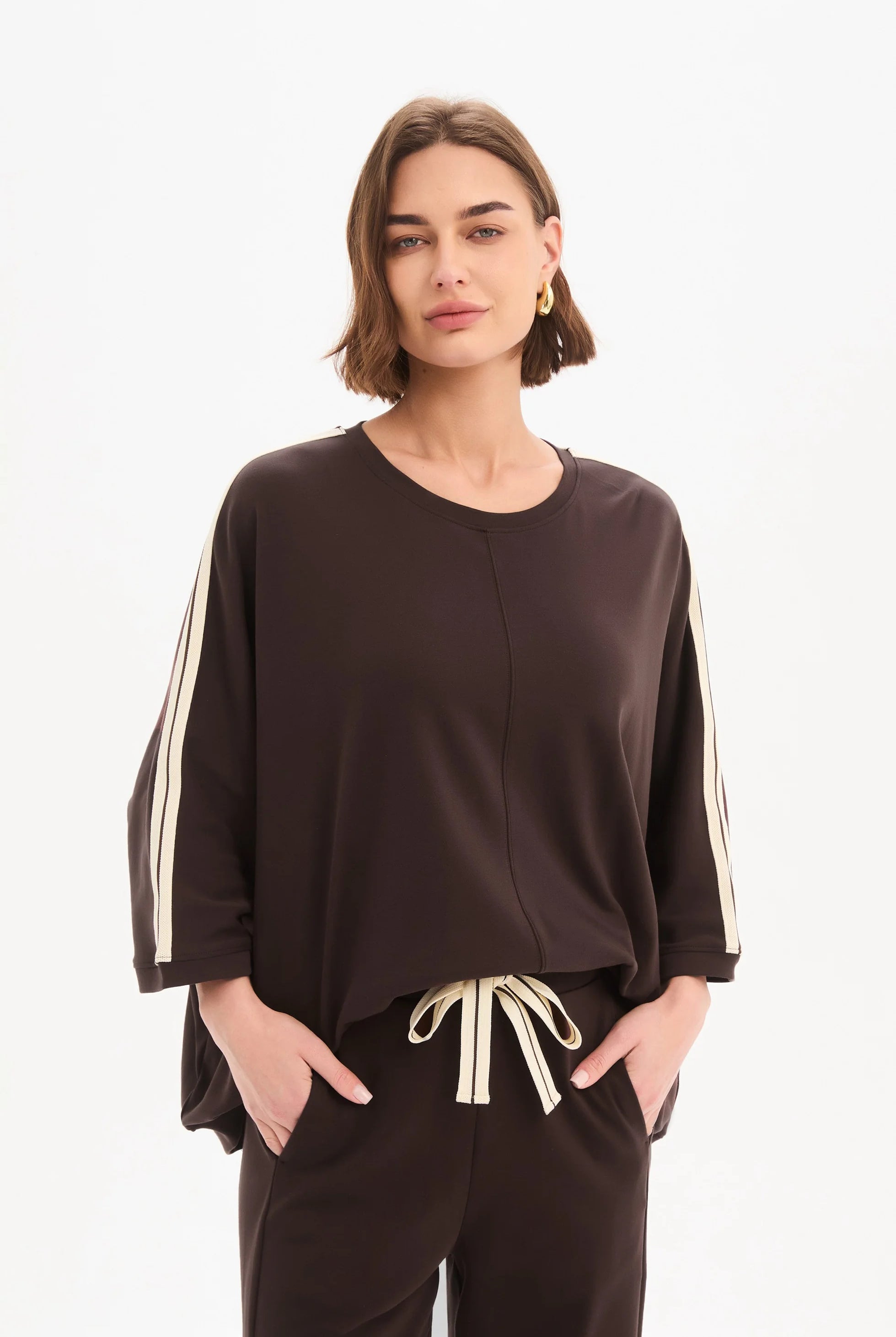 Woman wearing a brown outfit with white stripes on a white background