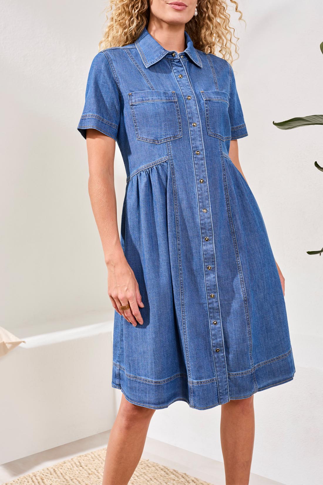 Woman wearing a blue denim dress against a neutral background