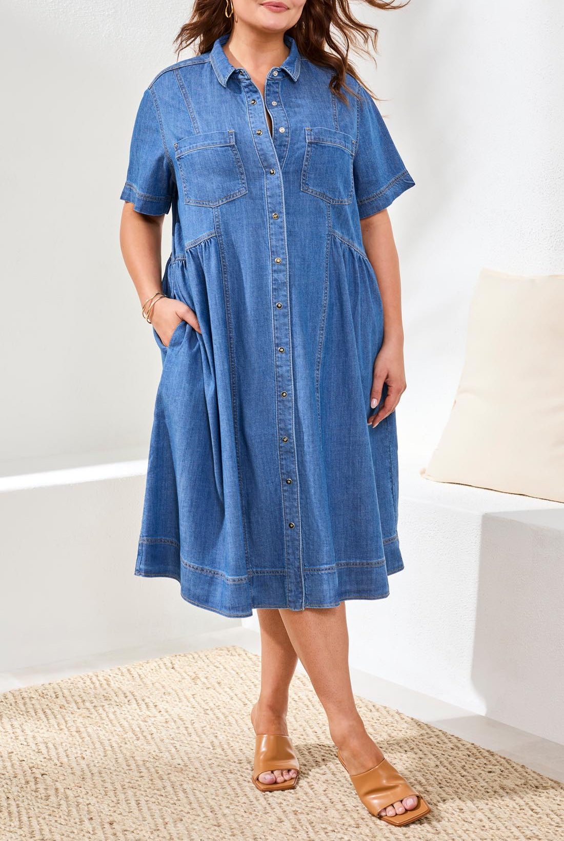 Woman wearing a blue denim dress standing on a textured surface with a white background