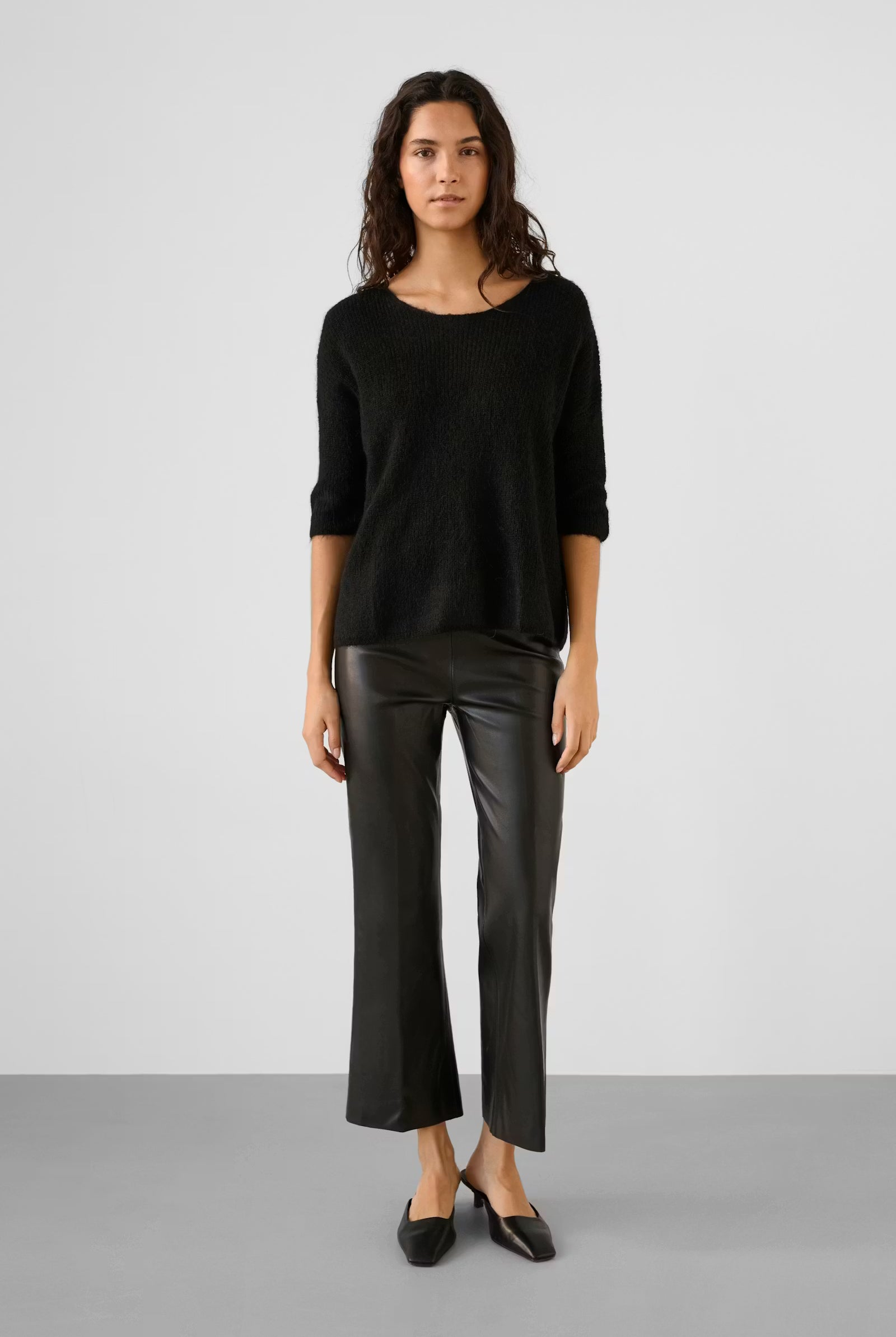 Woman wearing a black sweater and leather pants on a white background