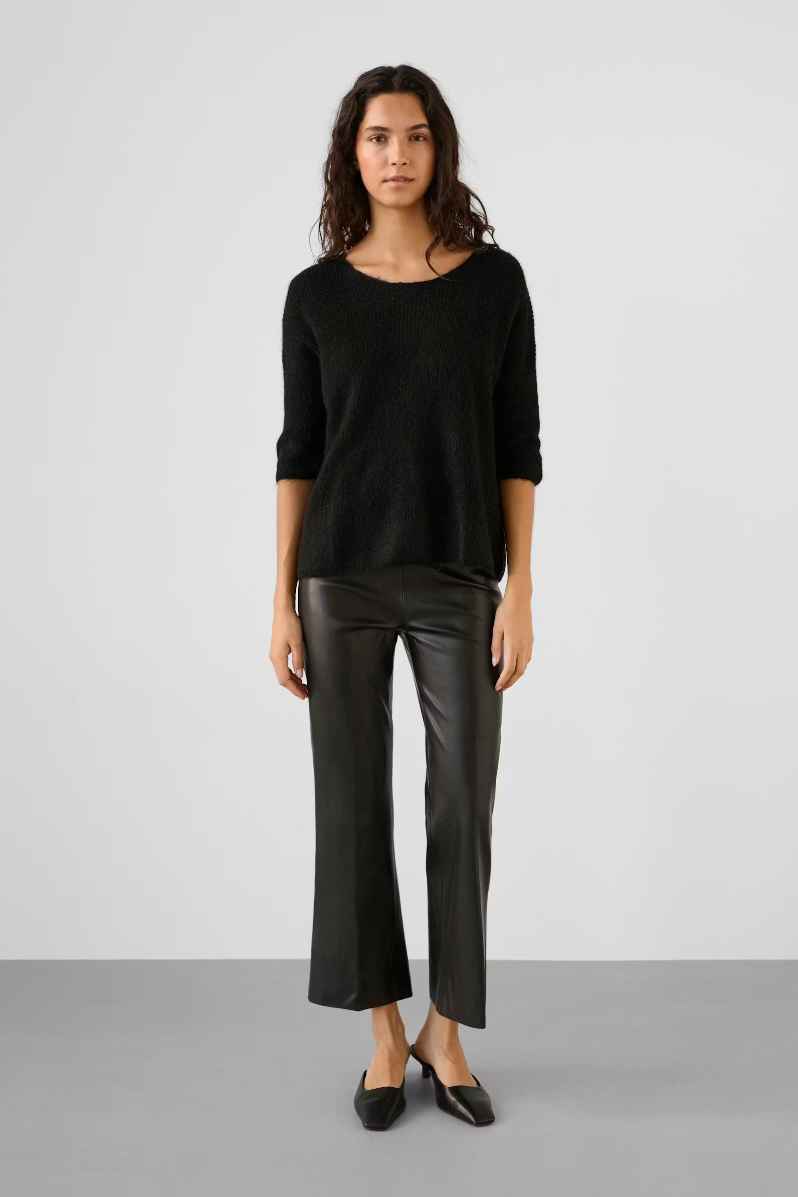 Woman wearing a black sweater and leather pants on a white background