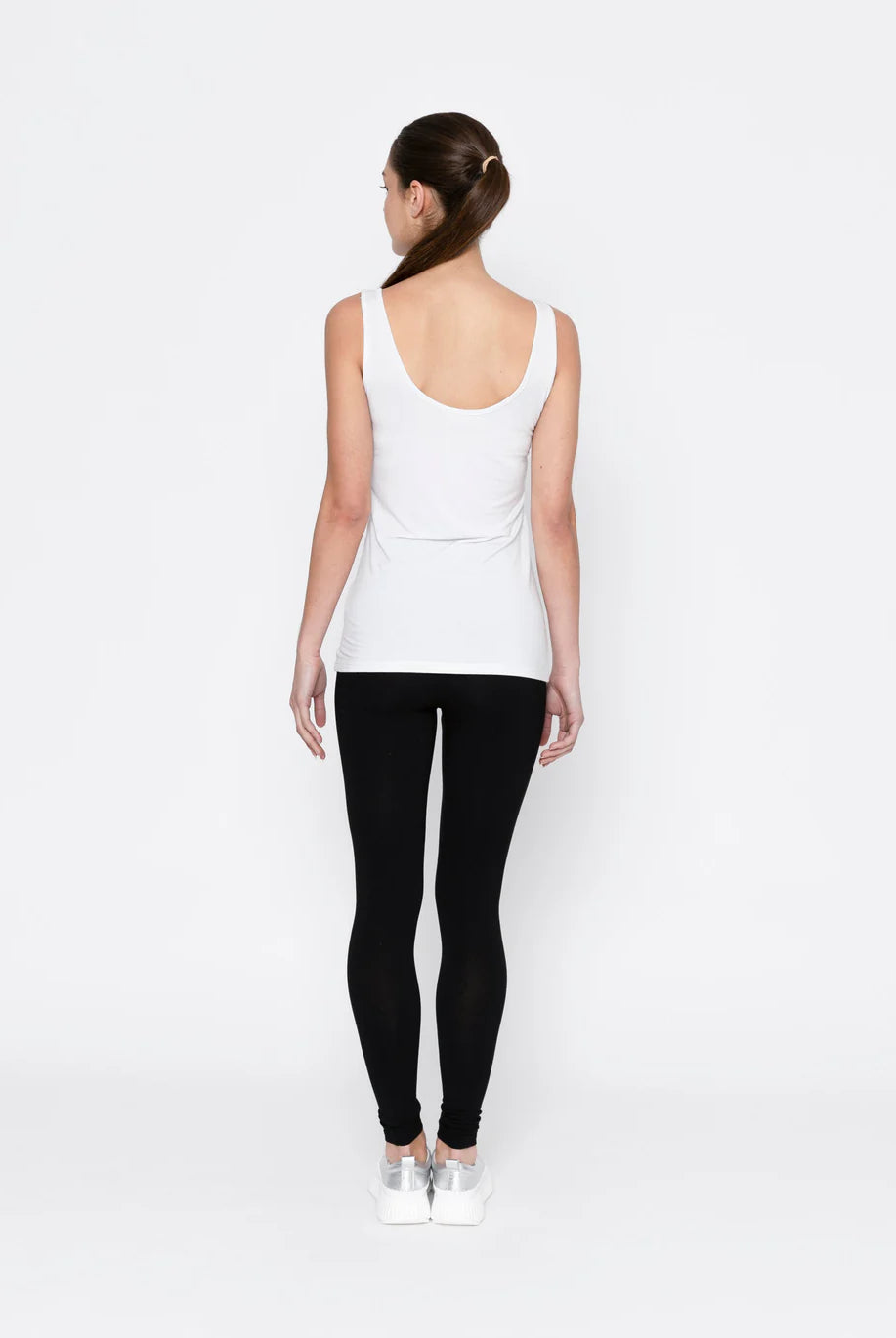 Person wearing a white tank top and black leggings on a white background