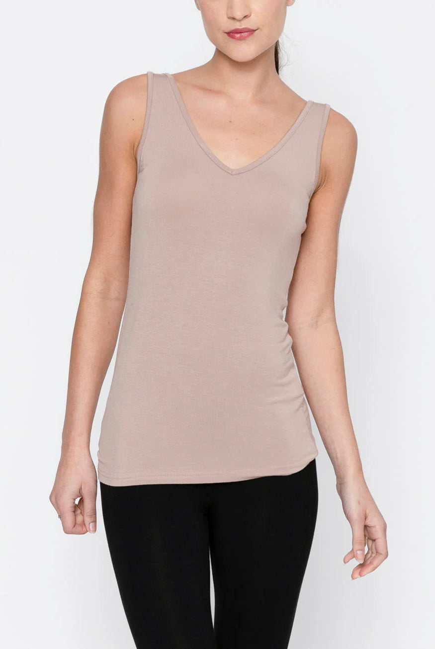 Woman wearing a beige tank top and black pants on a white background