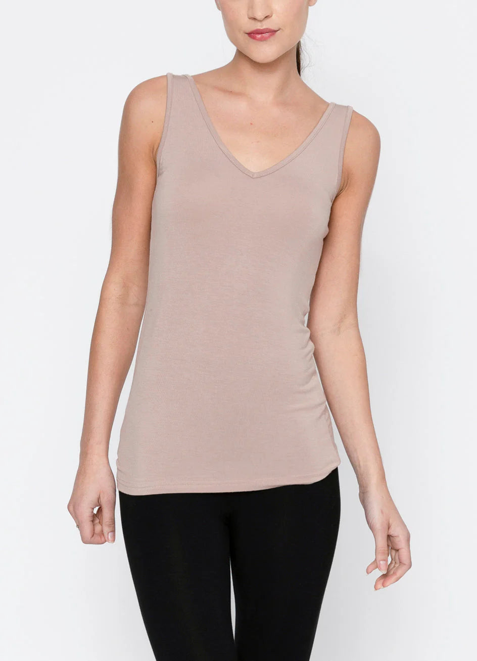 Woman wearing a beige tank top and black pants on a white background