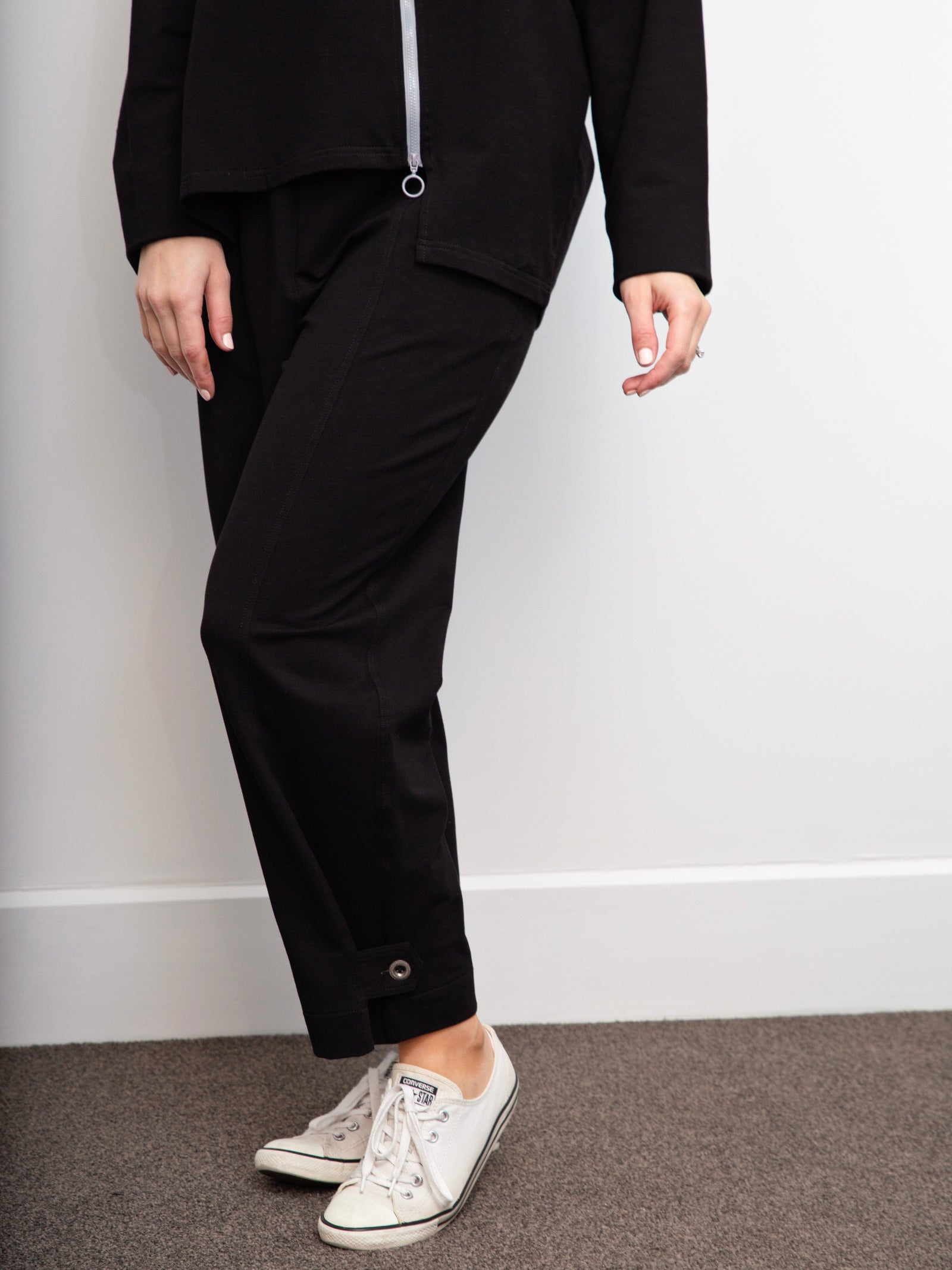 pair of legs wearing black pants and white sneakers