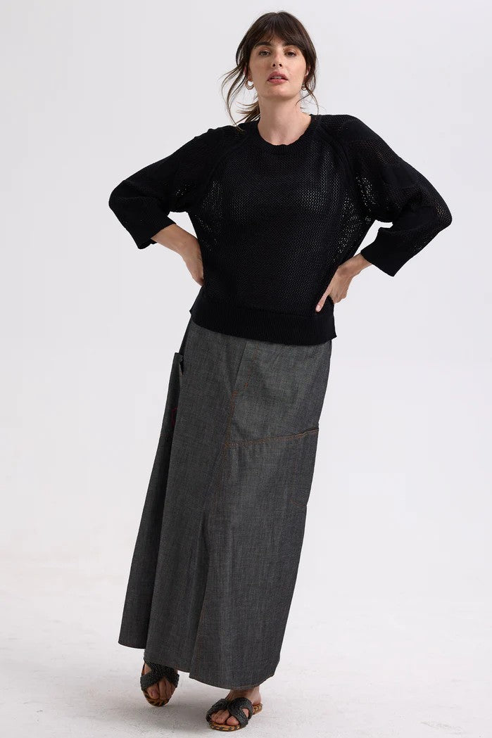 model wearing black sweater with heart sleeves and grey skirt