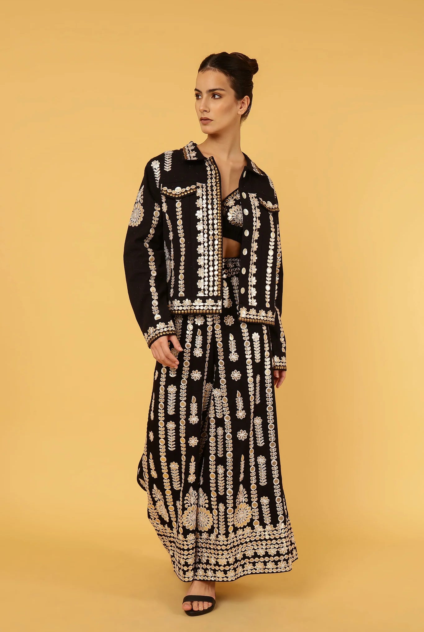 Woman wearing a black and gold patterned outfit on a yellow background