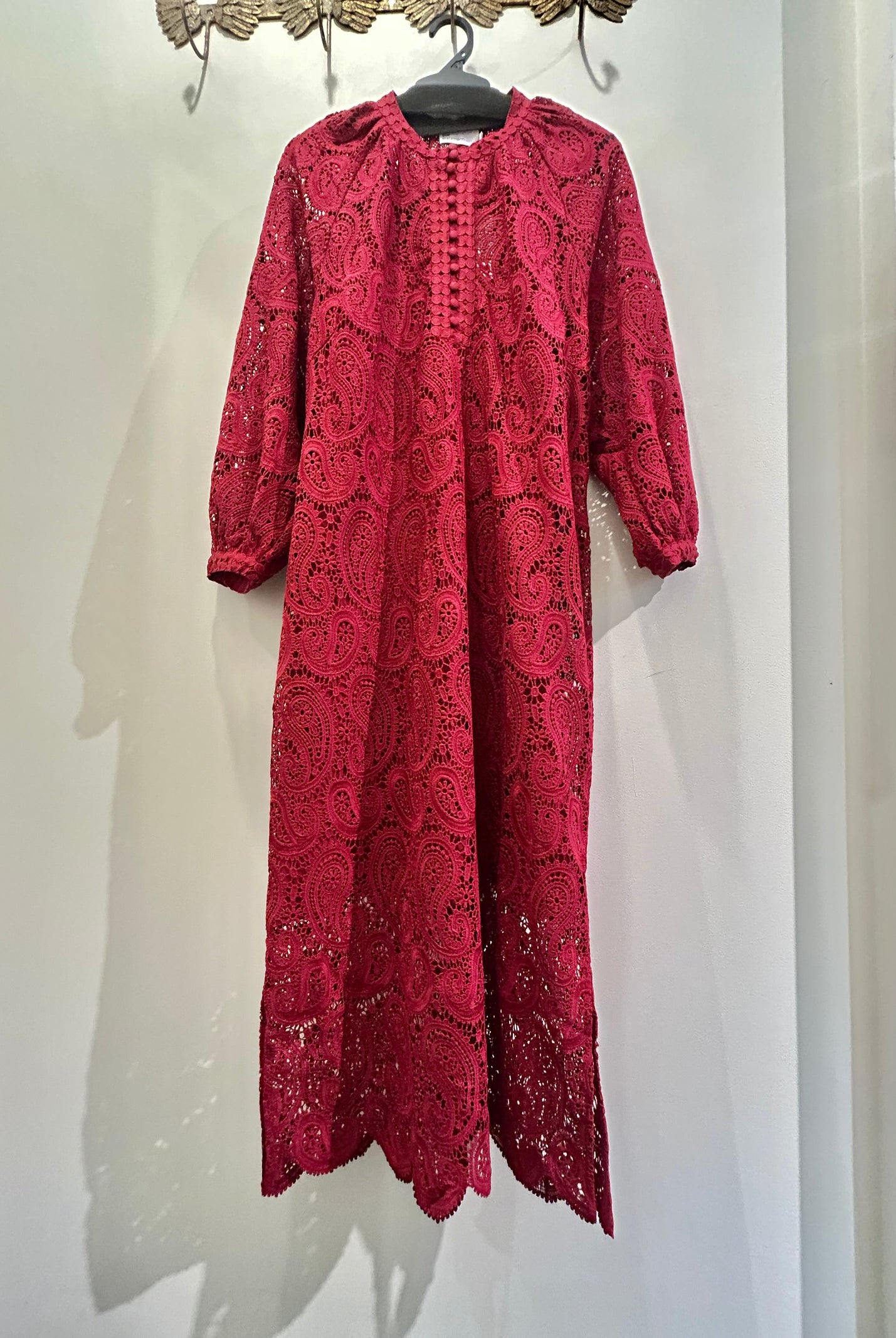 Red lace dress hanging on a white wall