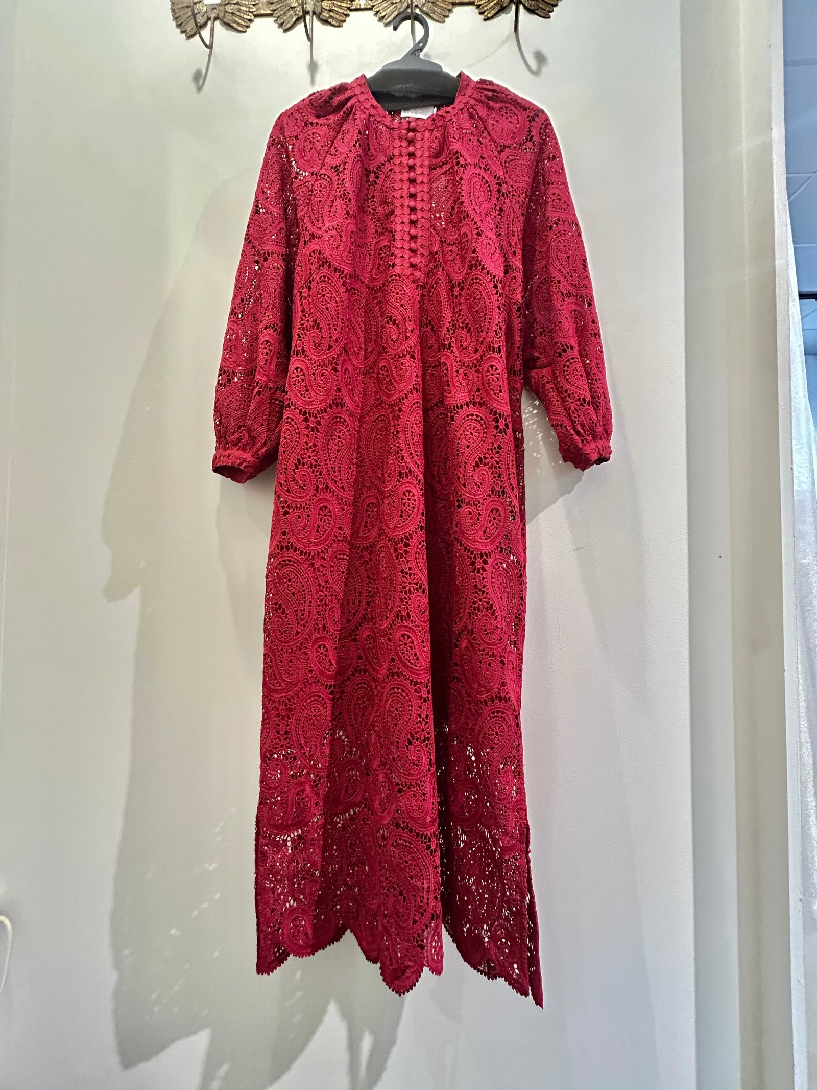 Red lace dress hanging on a white wall