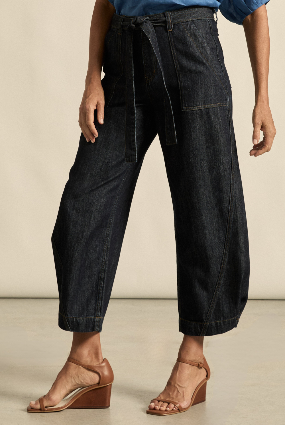 Person wearing black wide-leg pants with a belt on a neutral background