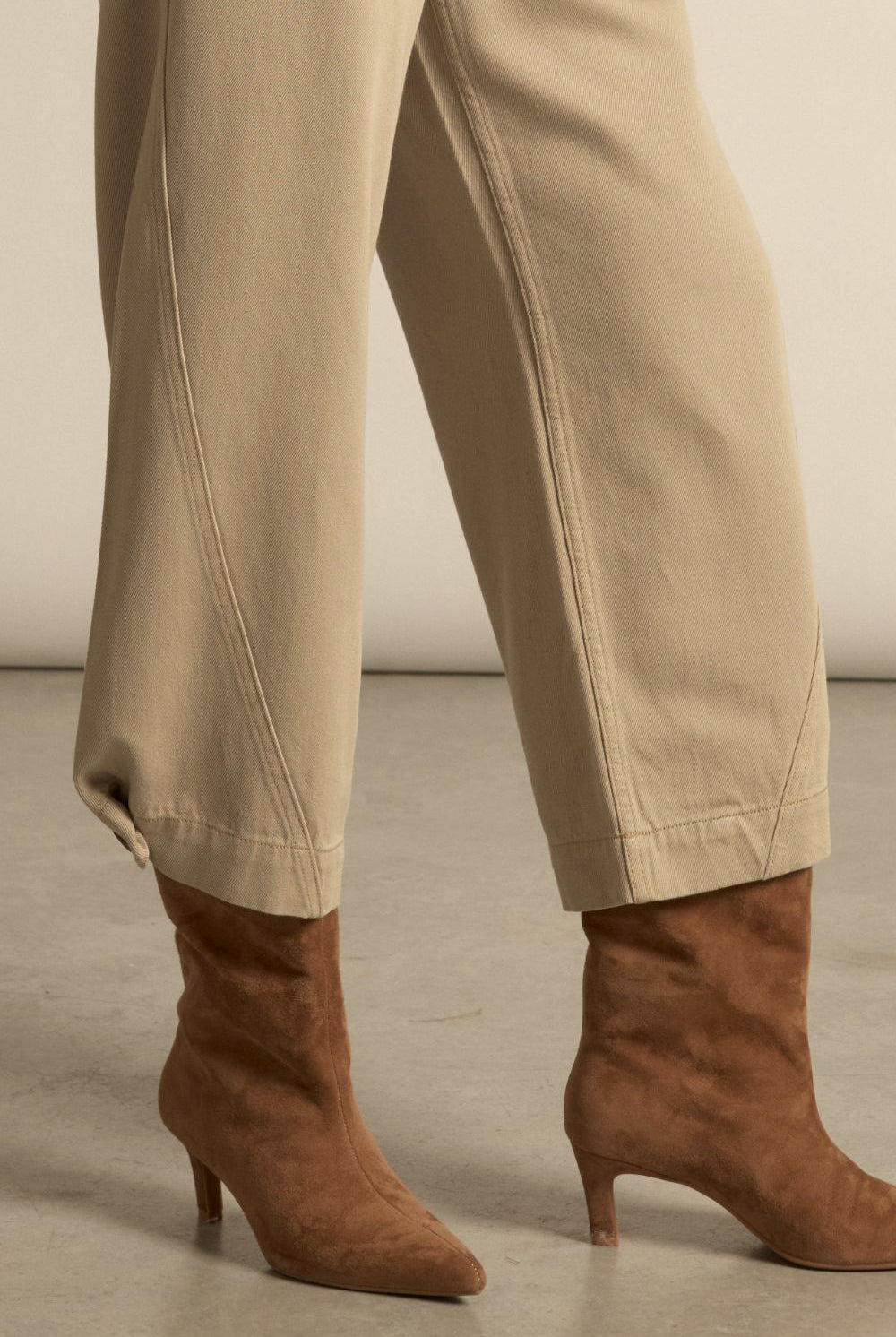 Beige pants and brown suede boots on a neutral background