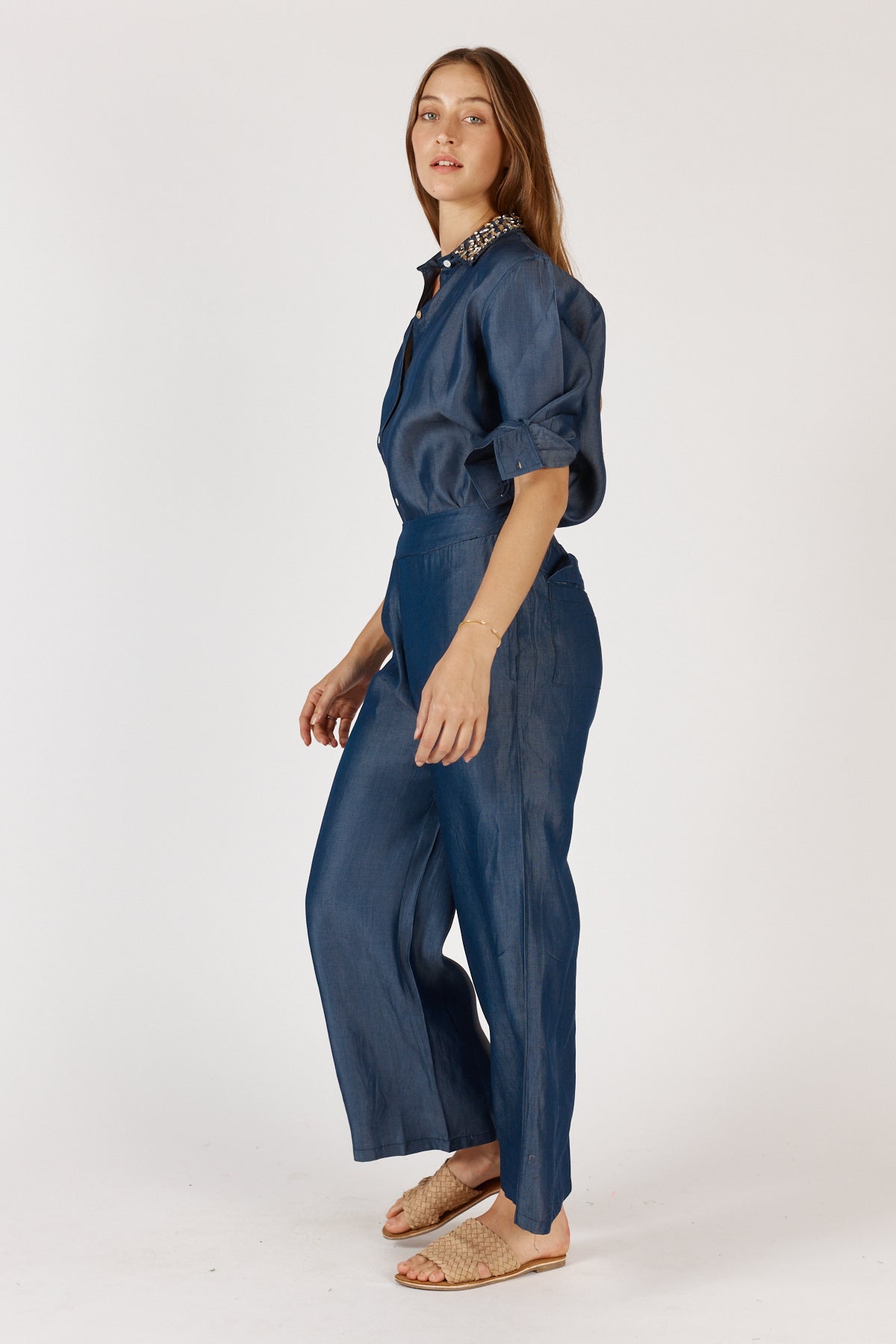 Women wearing a denim shirt and pant set on a white background side on view