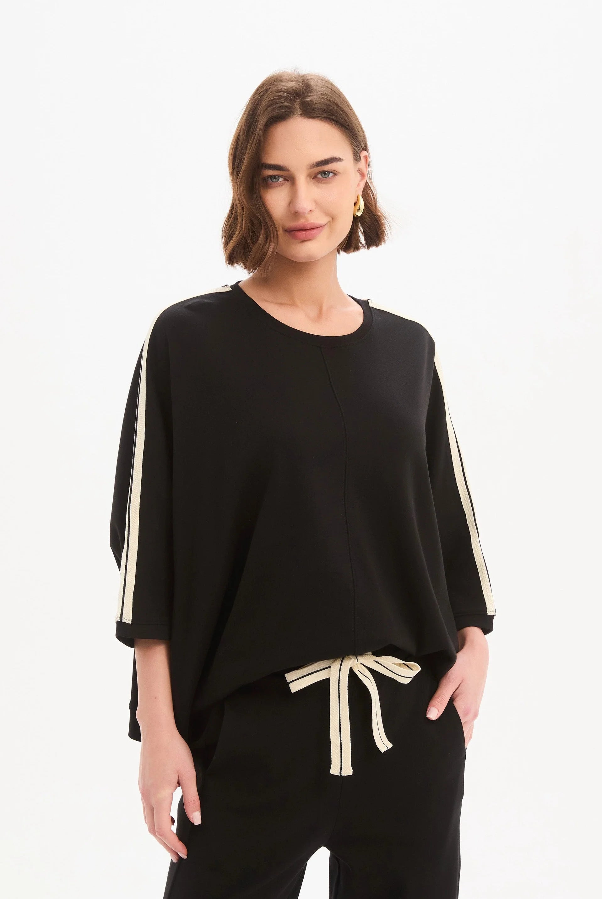 Woman wearing a black outfit with white stripes on a white background