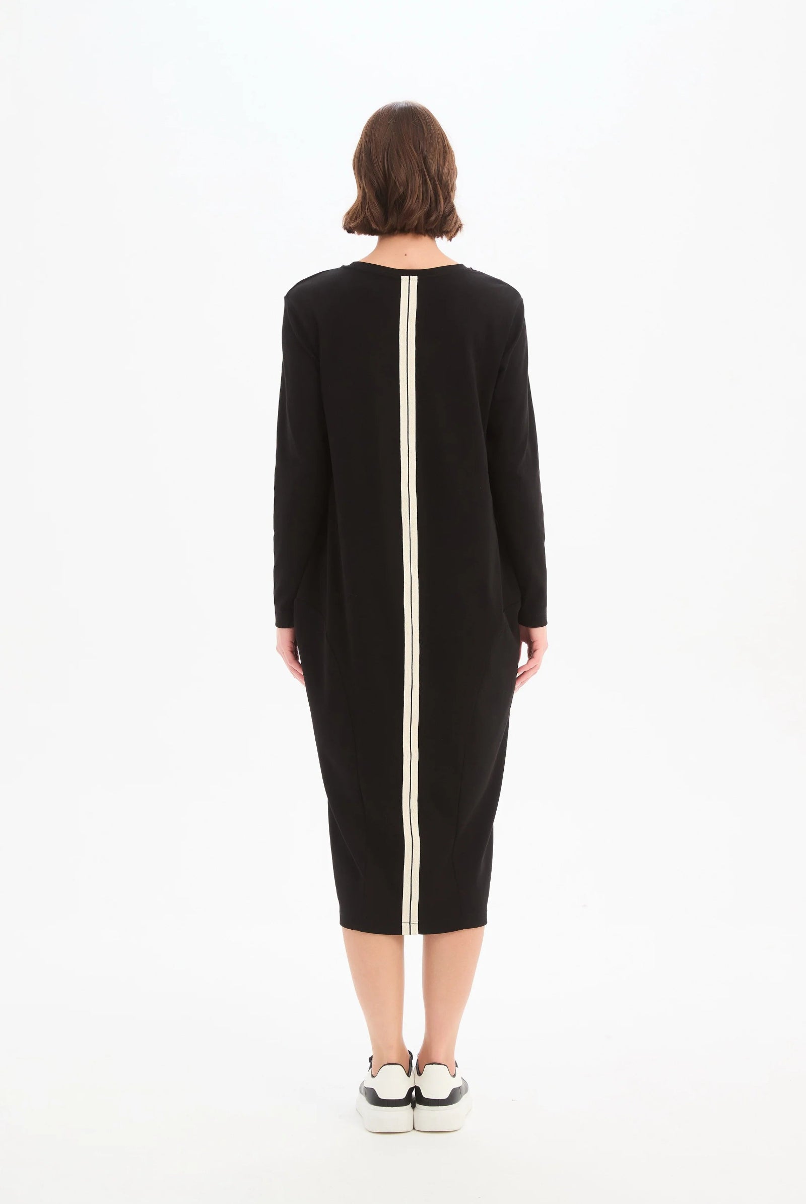 Person wearing a black dress with a white zipper on a white background