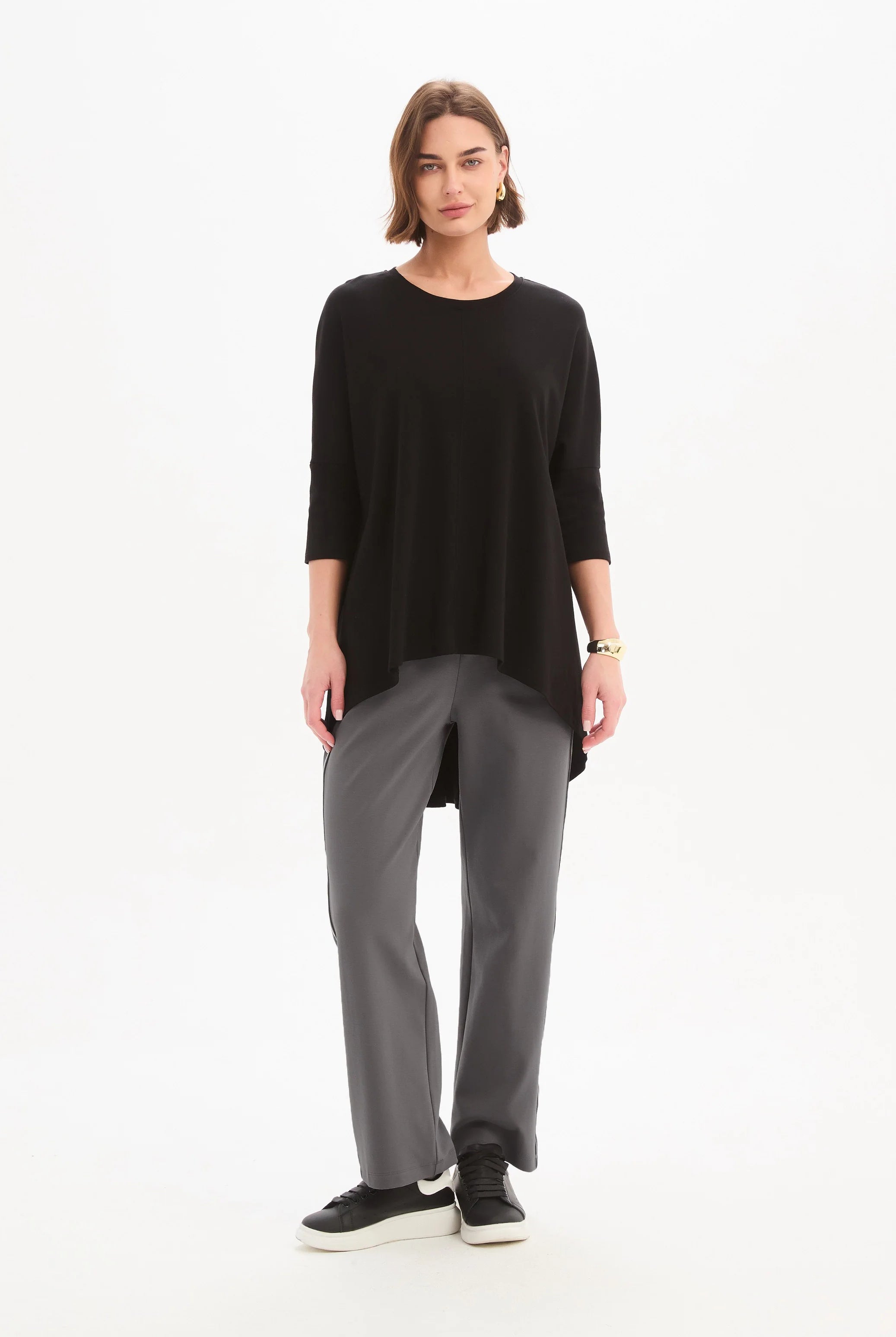 women wearing a black top and grey pants on a plain background