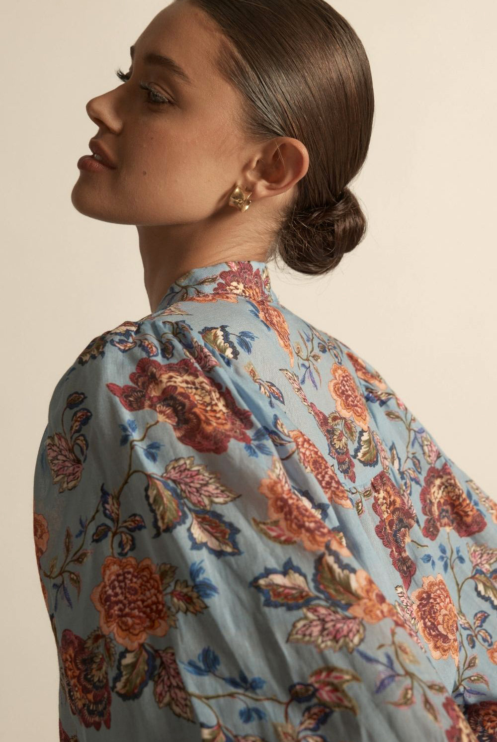 Woman wearing a floral blouse with a neutral background