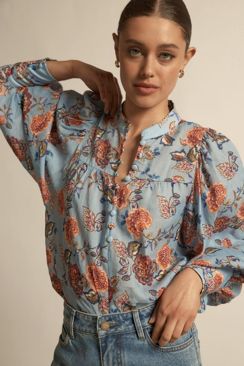 Woman wearing a floral blouse with a neutral background