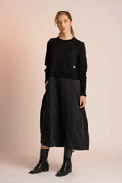 Woman wearing a black outfit with a long skirt on a beige background