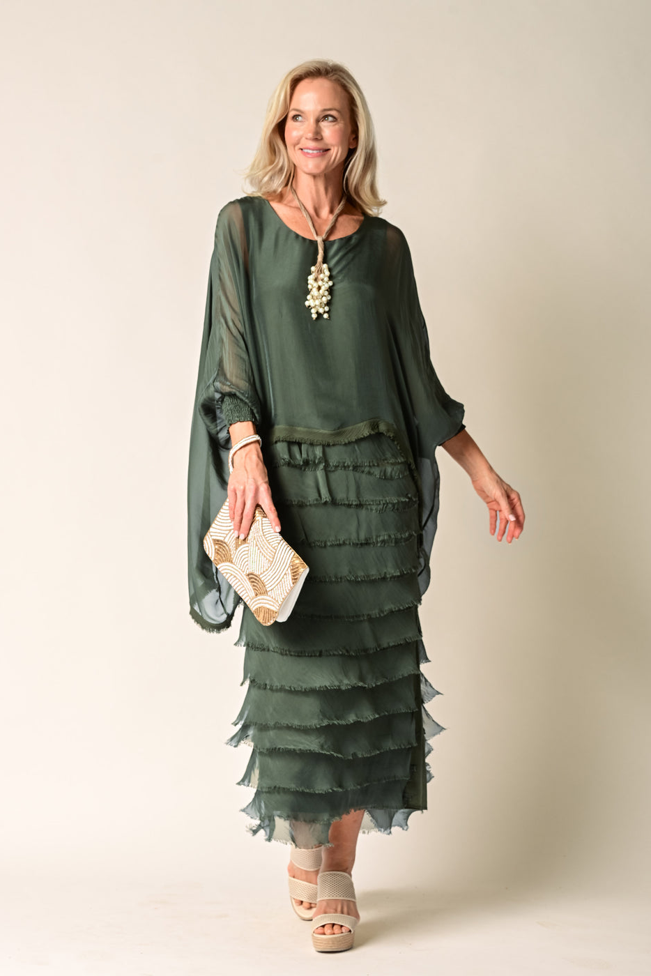 Woman wearing a green dress with ruffled layers against a plain background