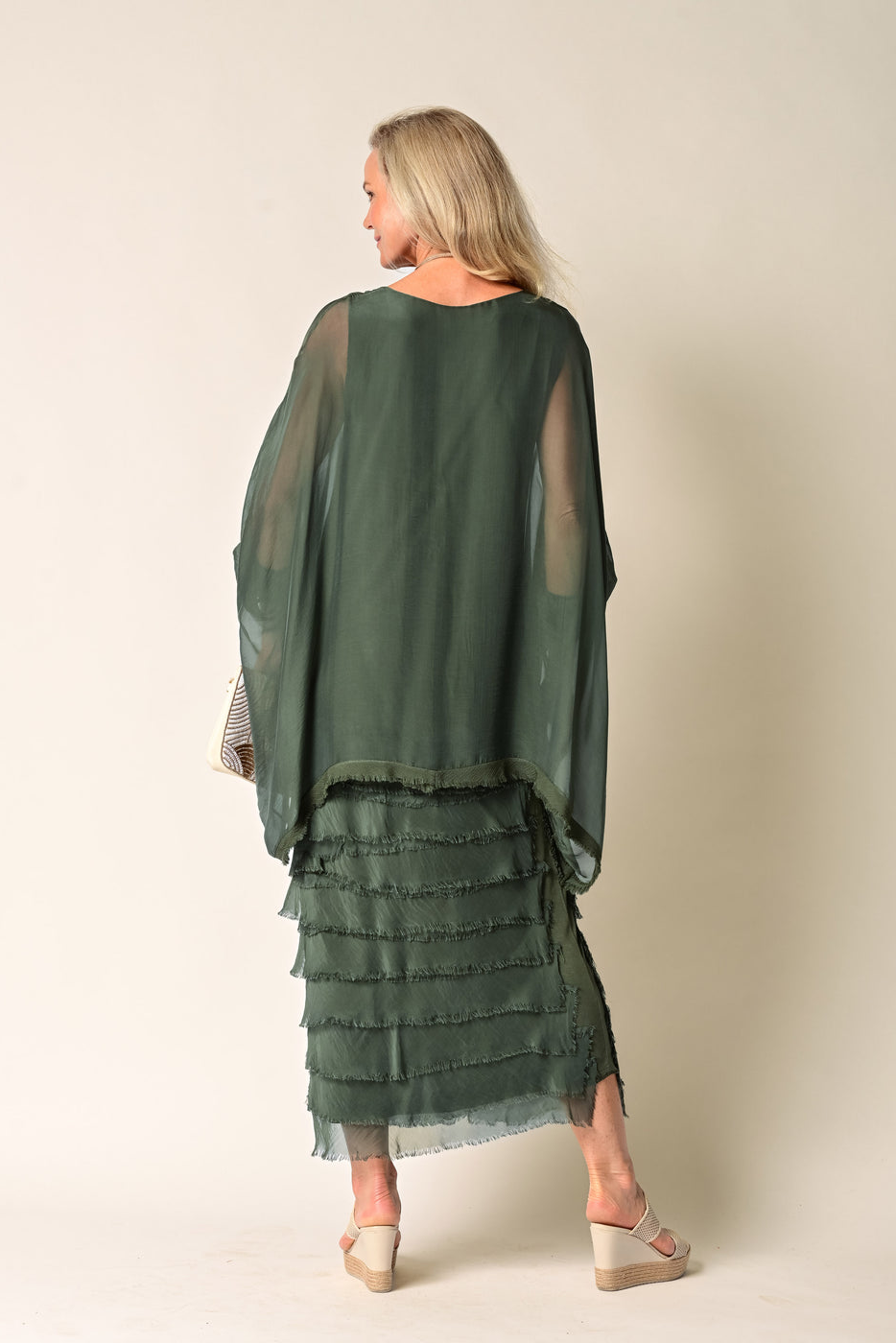 Woman wearing a green layered dress against a beige background