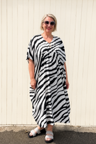 women wearing a zebra maxi dress against a white wall